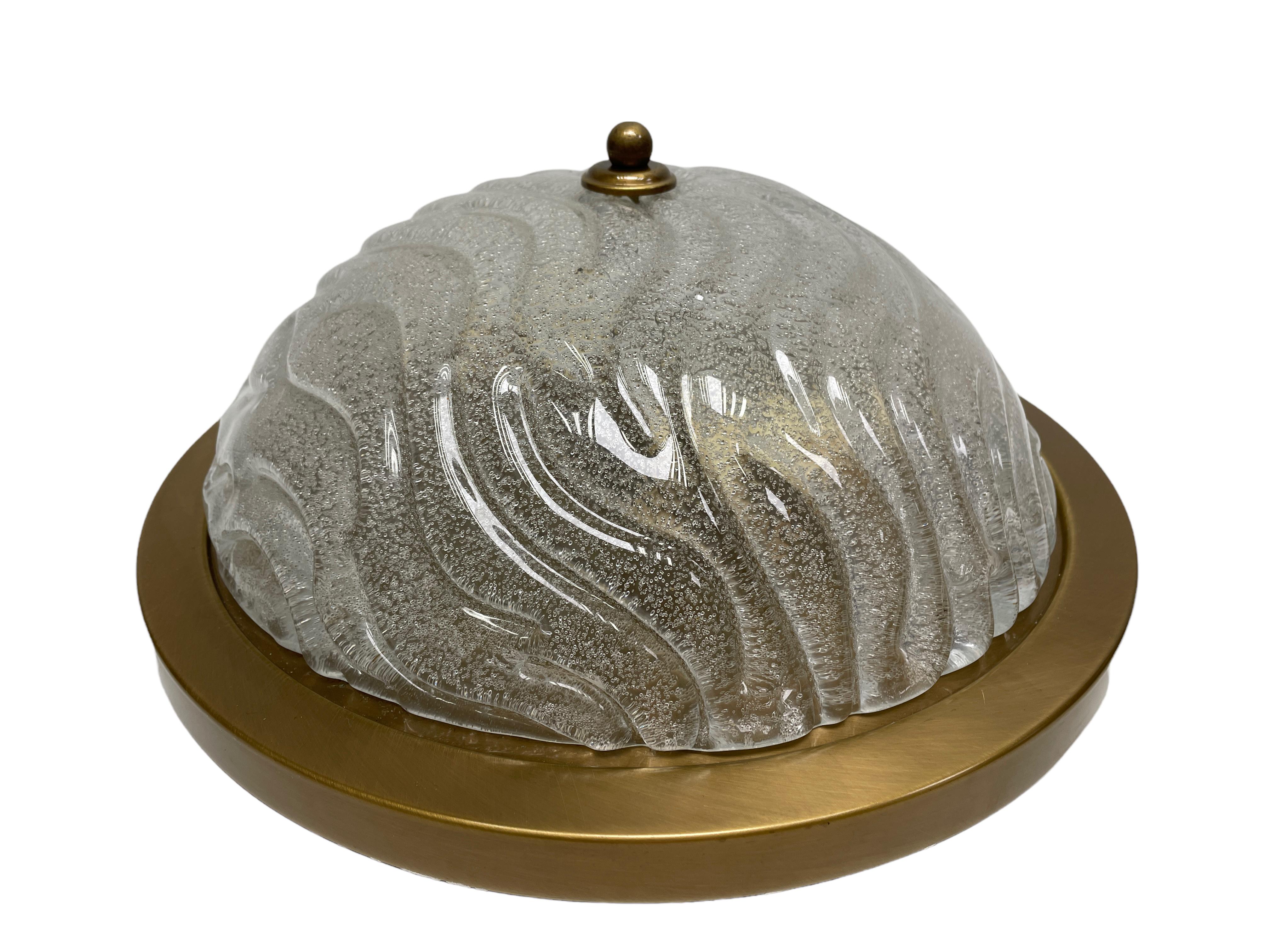 A beautiful large flush mount by German manufacturer Fischer Leuchten. The large heavy glass element is supported by a burnished brass plate with two light sources. Beautiful wave clear glass on a metal fixture. The Fixture requires two European E27