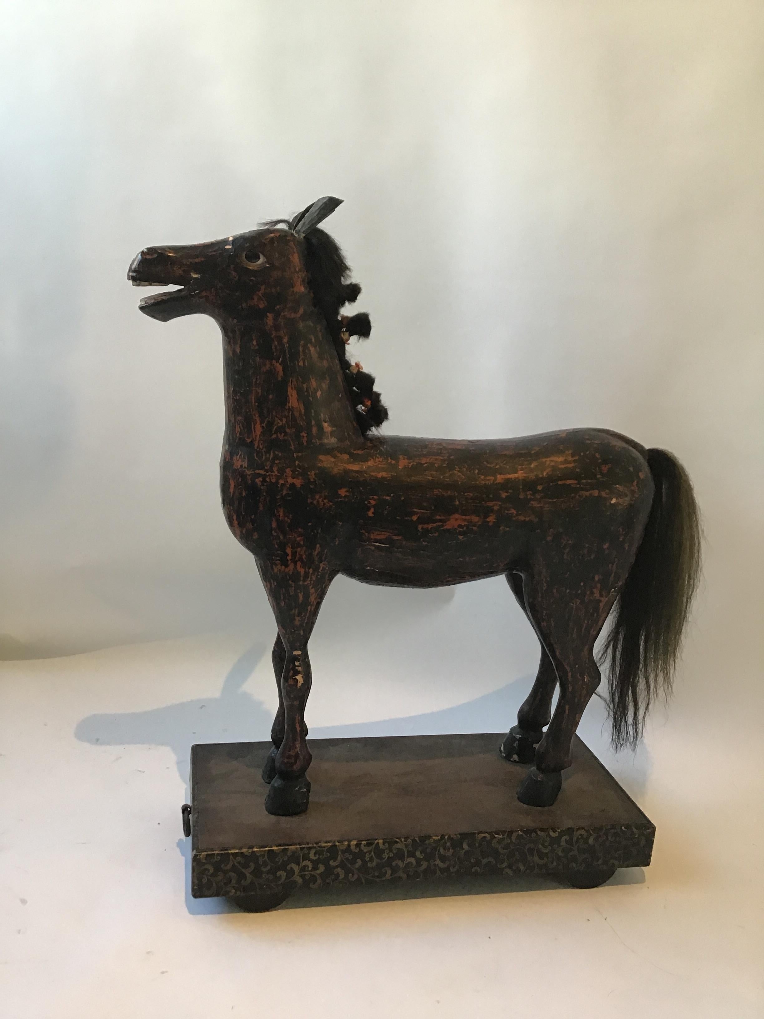 Large Folk Art painted carved wood horse on base with wheels. Real horse hair, glass eyes. Chips in paint.