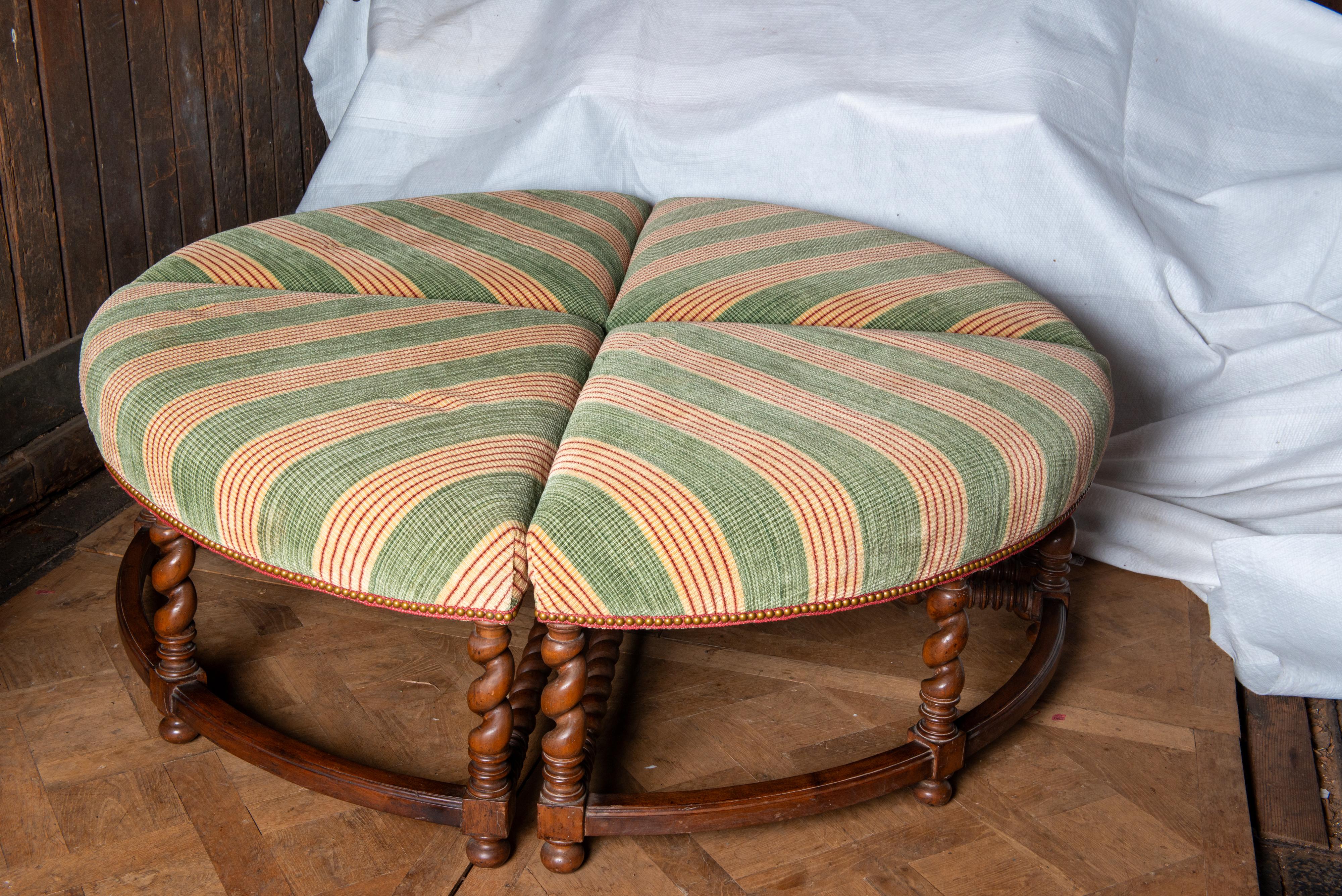 An unusual large four piece round ottoman, bench, or bourne. Each piece is pie shaped and upholstered in a smart green and red striped substantial fabric. The wood base has carved barley twist leg ending in bun feet. The front stretchers are curved.