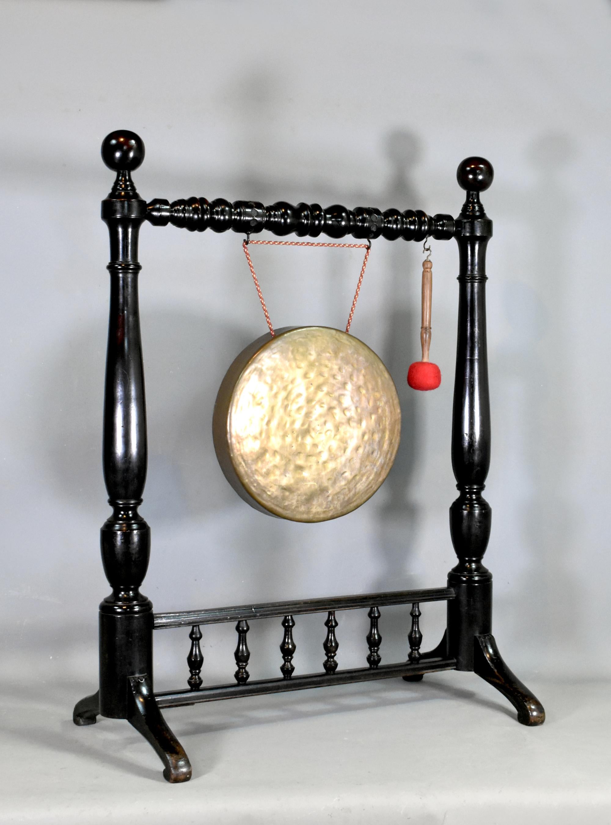 Large Framed Dinner Gong in Mahogany 

This impressive bronze gong hangs from a well-crafted turned stand. 

The original hand-crafted gong offers a substantial sound, when struck with the hammer / beater. 

The outer columns are turned, very sturdy