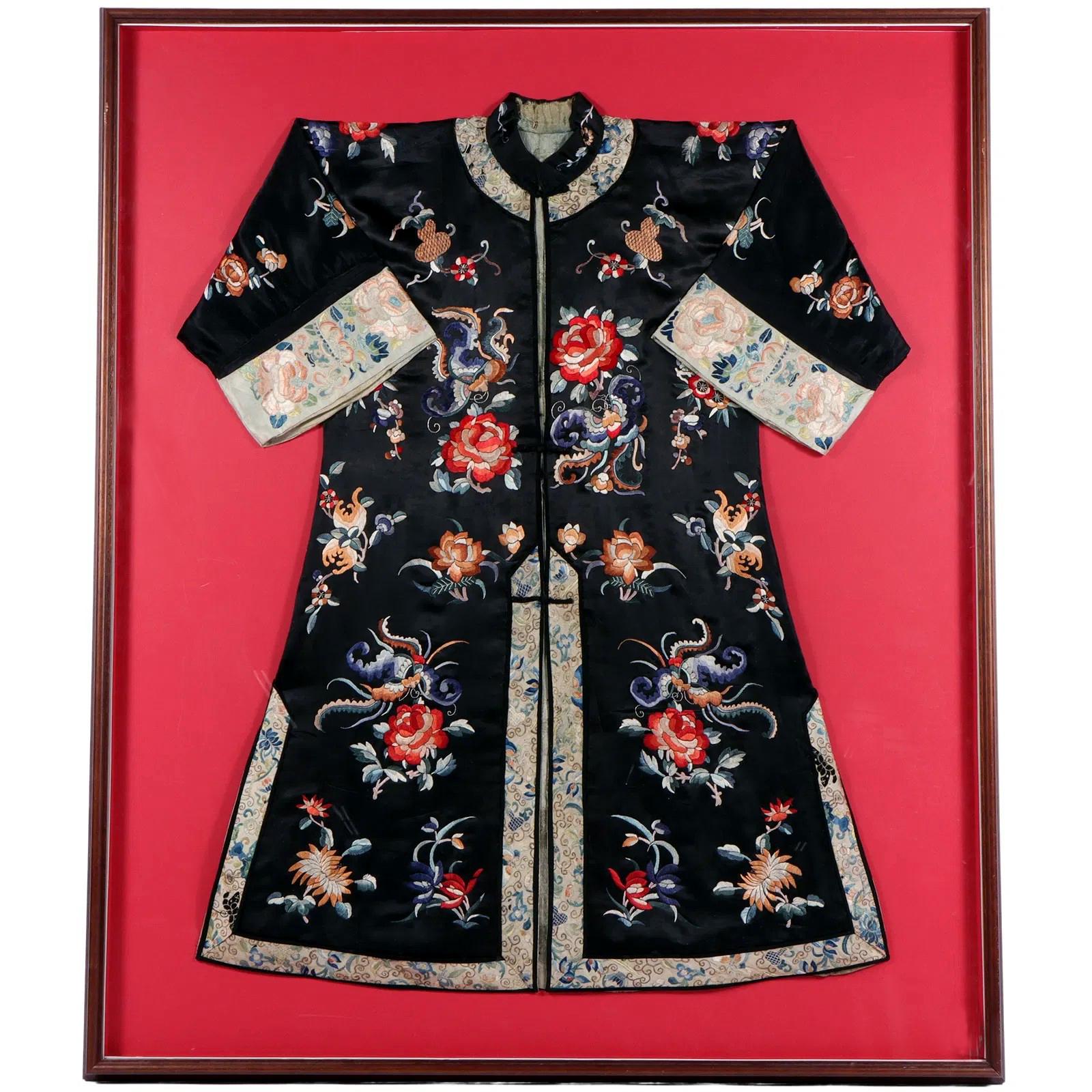 Un manteau de femme en soie teintée noire à larges manches de la Chine de la fin de la dynastie Qing (fin du XIXe siècle - début du XXe siècle), monté avec les manches pliées et présenté dans un cadre de boîte d'ombre rouge corail comme une