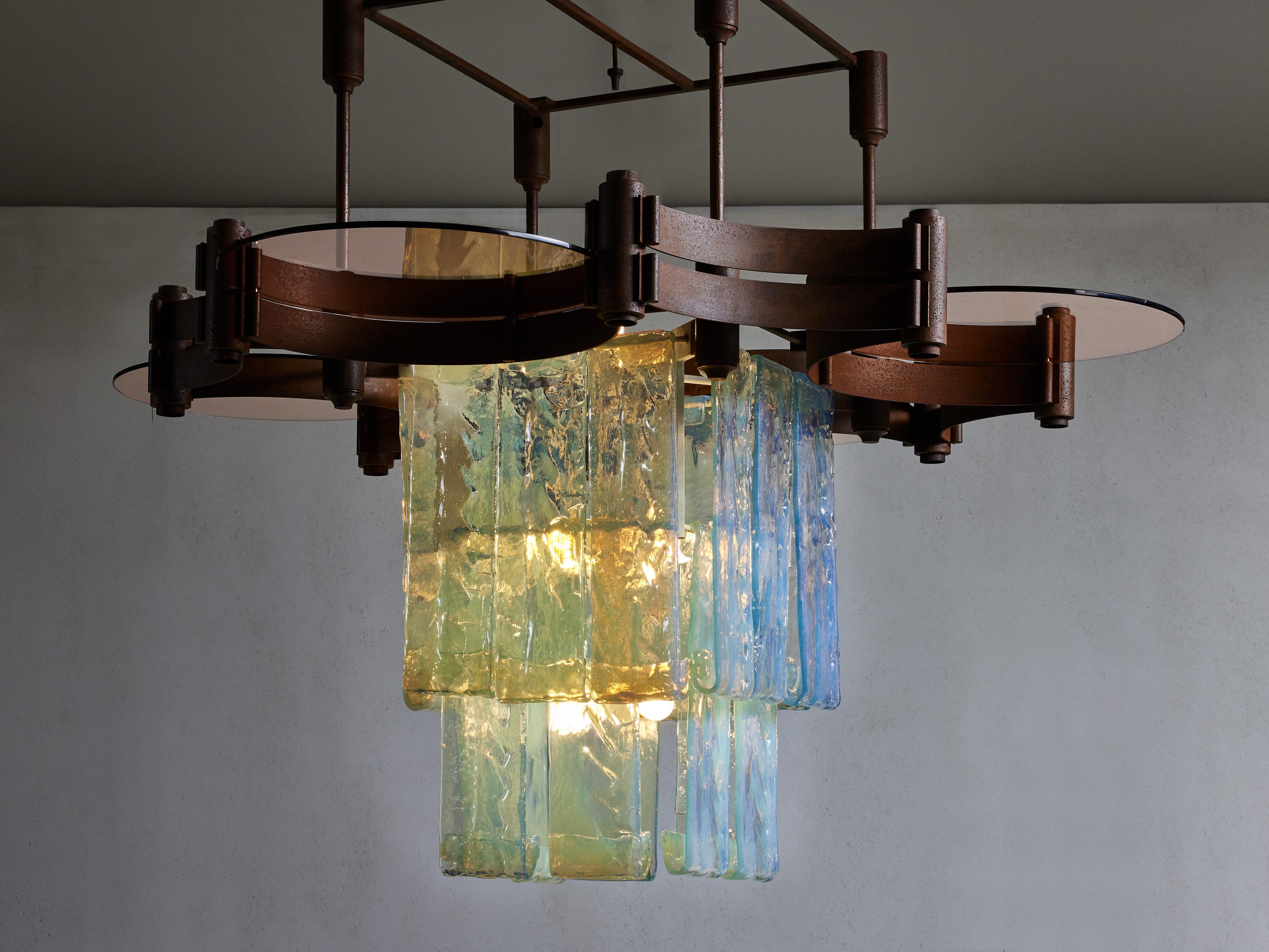 Grand lustre en métal oxydé réalisé par les Fratelli Toso dans les années 1960, composé d'une grande structure, de quatre plaques rondes en verre fumé et de vingt pièces en verre Laguna en opalino bluino.