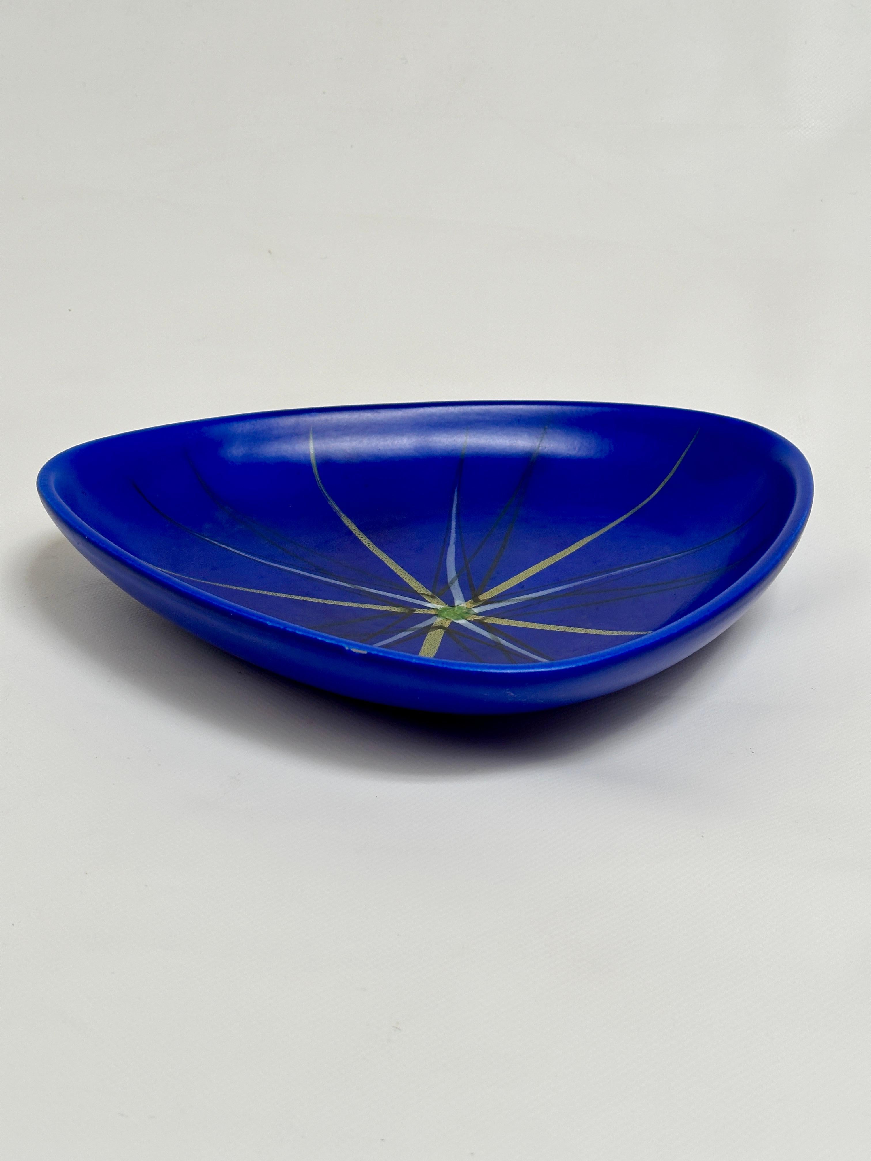 Large triangulated dish in vibrant satin blue glaze animated in its center by a stellar pattern.

André Baud is already an artist with a solid reputation when he moves to Vallauris in 1942.
He actively participates in the reputation of this artistic