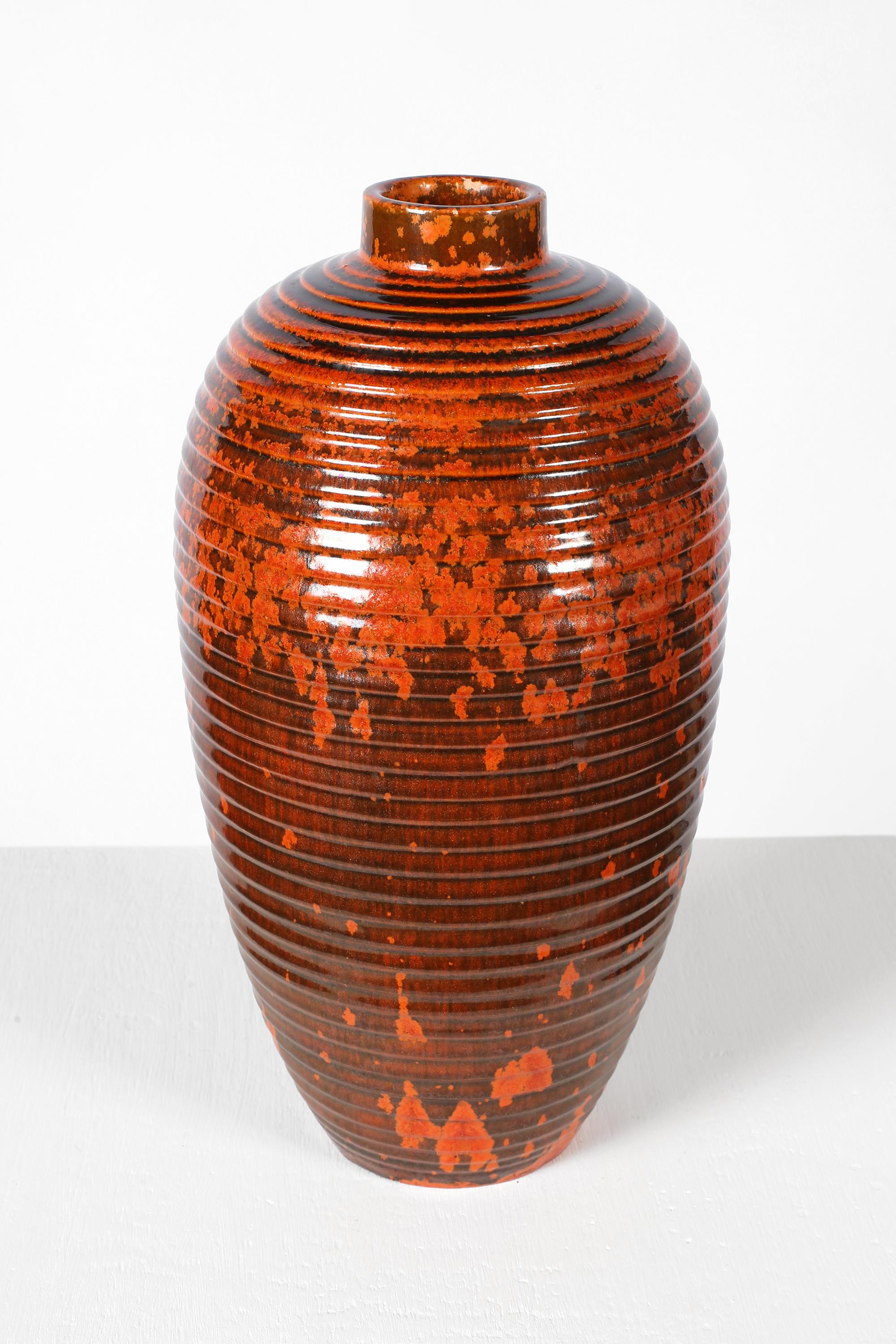 Vaso in ceramica smaltata color arancio bruciato e nero, alto e a fasce, realizzato da Atelier A Primavera e dalla Fabbrica di Ceramica d'Arte di Bordeaux. Probabilmente prodotto per i grandi magazzini Printemps di Parigi, stampato. Francese, anni