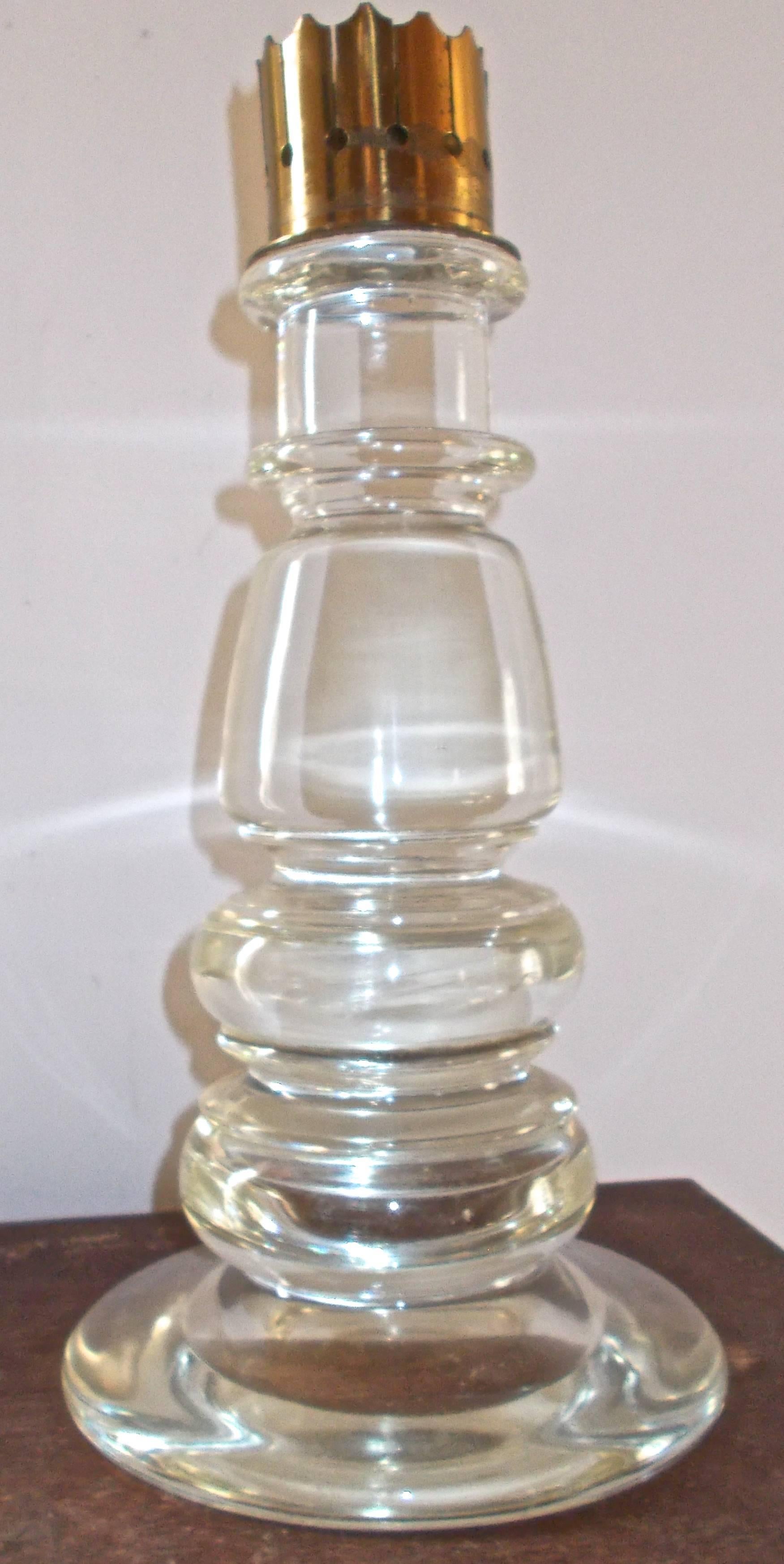 A large clear glass candlestick composed of circular 'turnings', topped with a brass bobeche. Unsigned with a cleaned pontil. Measures: H. 35.5 cm., D. 19 cm.