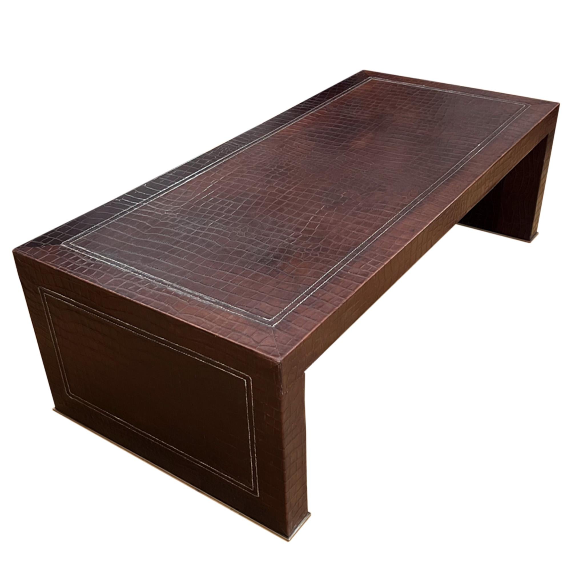 Cette fabuleuse table basse a été fabriquée en France dans les années 1970. 

Fabriqué à partir d'un riche cuir de couleur marron foncé, la surface a été pressée pour ressembler à une peau de crocodile. Il a ensuite été finement cousu pour créer des