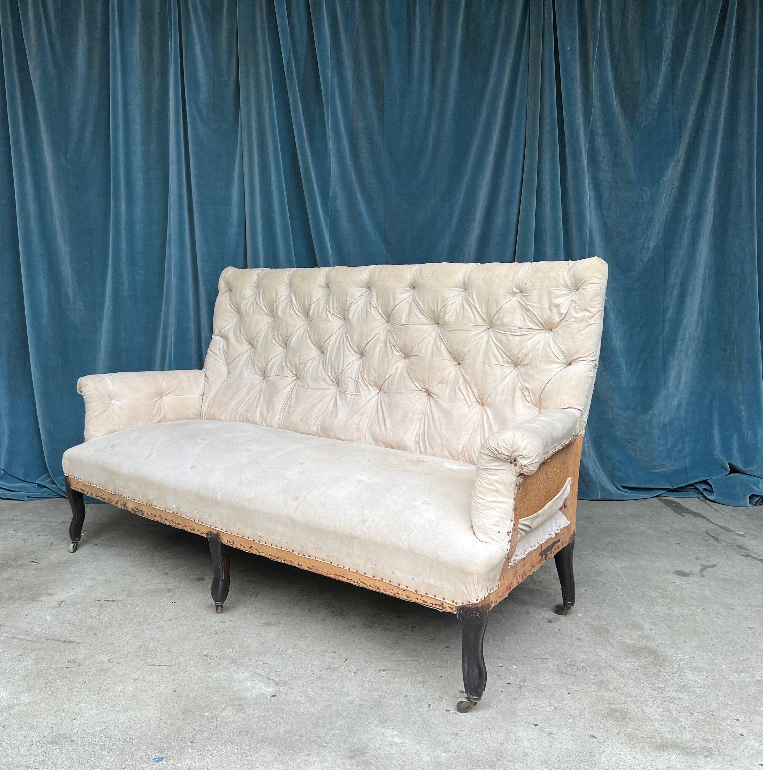 A large scale French 19th century Napoleon III high backed sofa with cabriole legs. The back of this sofa is heavily tufted as are the rolled arms - adding grandeur and sophistication to its design. The sofa has been stripped down to the muslin and