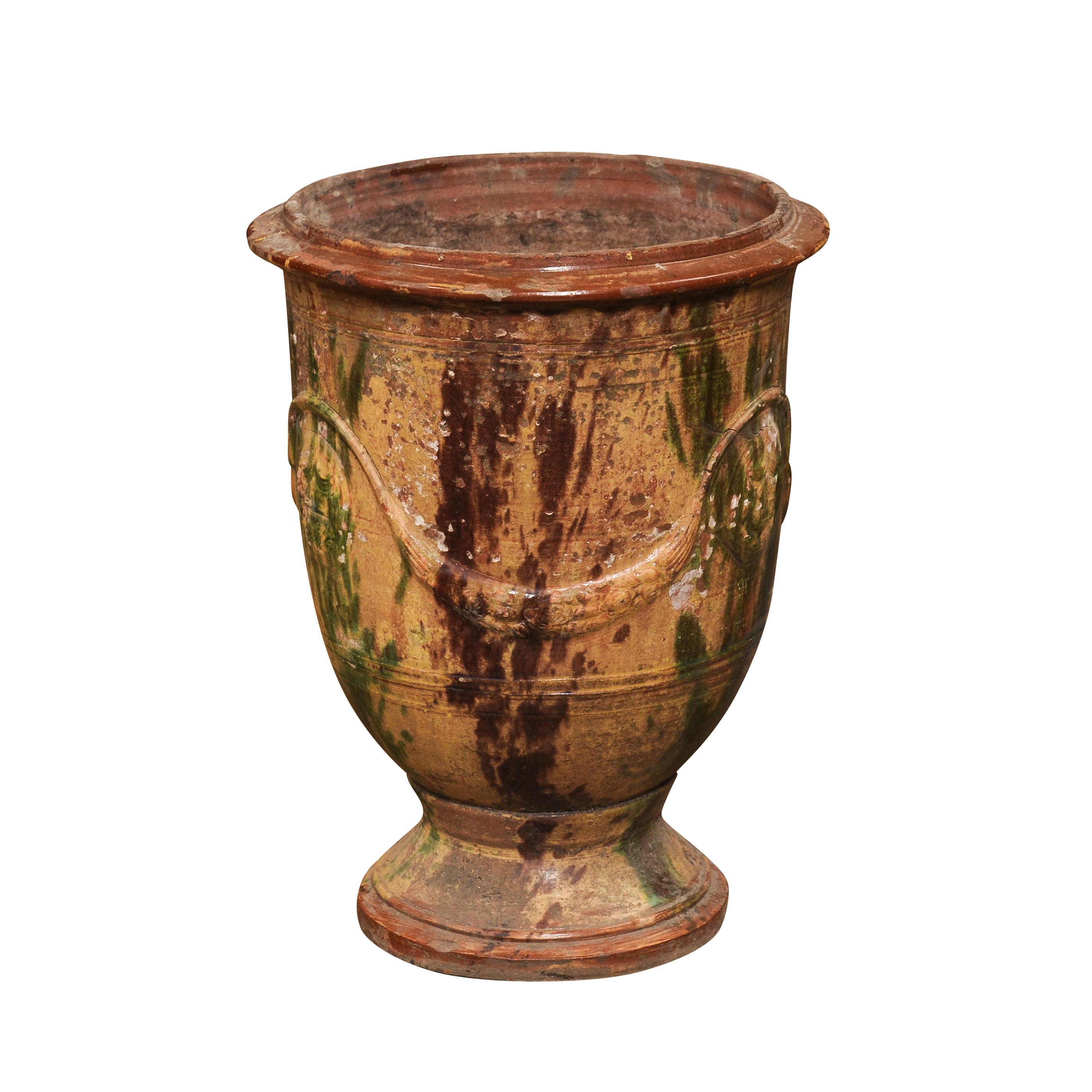 A large French Anduze Boisset jar from the 19th century with dark brown and green drip glaze and swag decoration in raised relief. Imbued with an aura of rustic elegance and traditional craftsmanship, this large French Anduze jar hailing from the