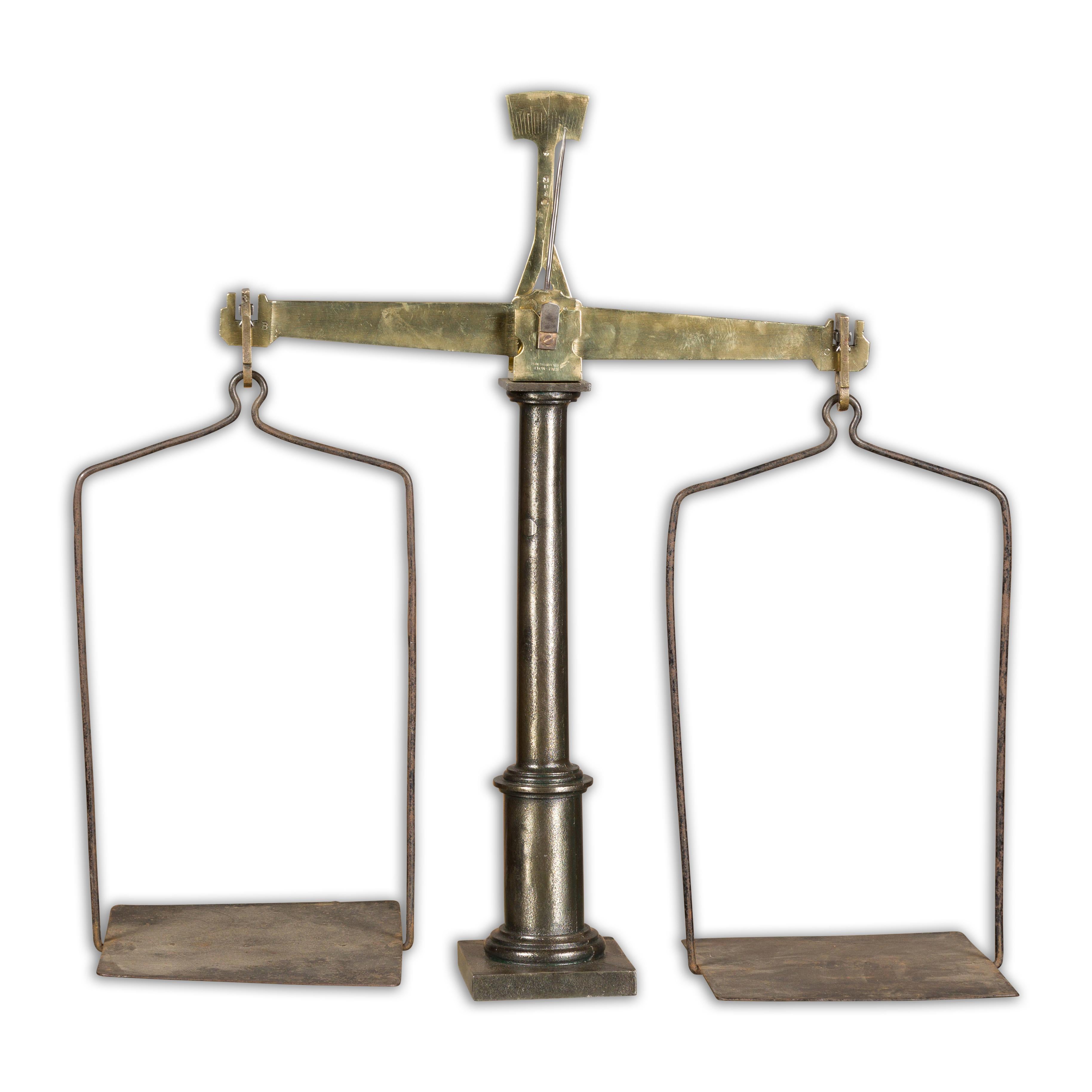A French brass and steel scale from the 19th century with central column and two weighing pans. Embrace the charm and sophistication of the 19th century with this exquisite French brass and steel scale, a testament to the craftsmanship and design