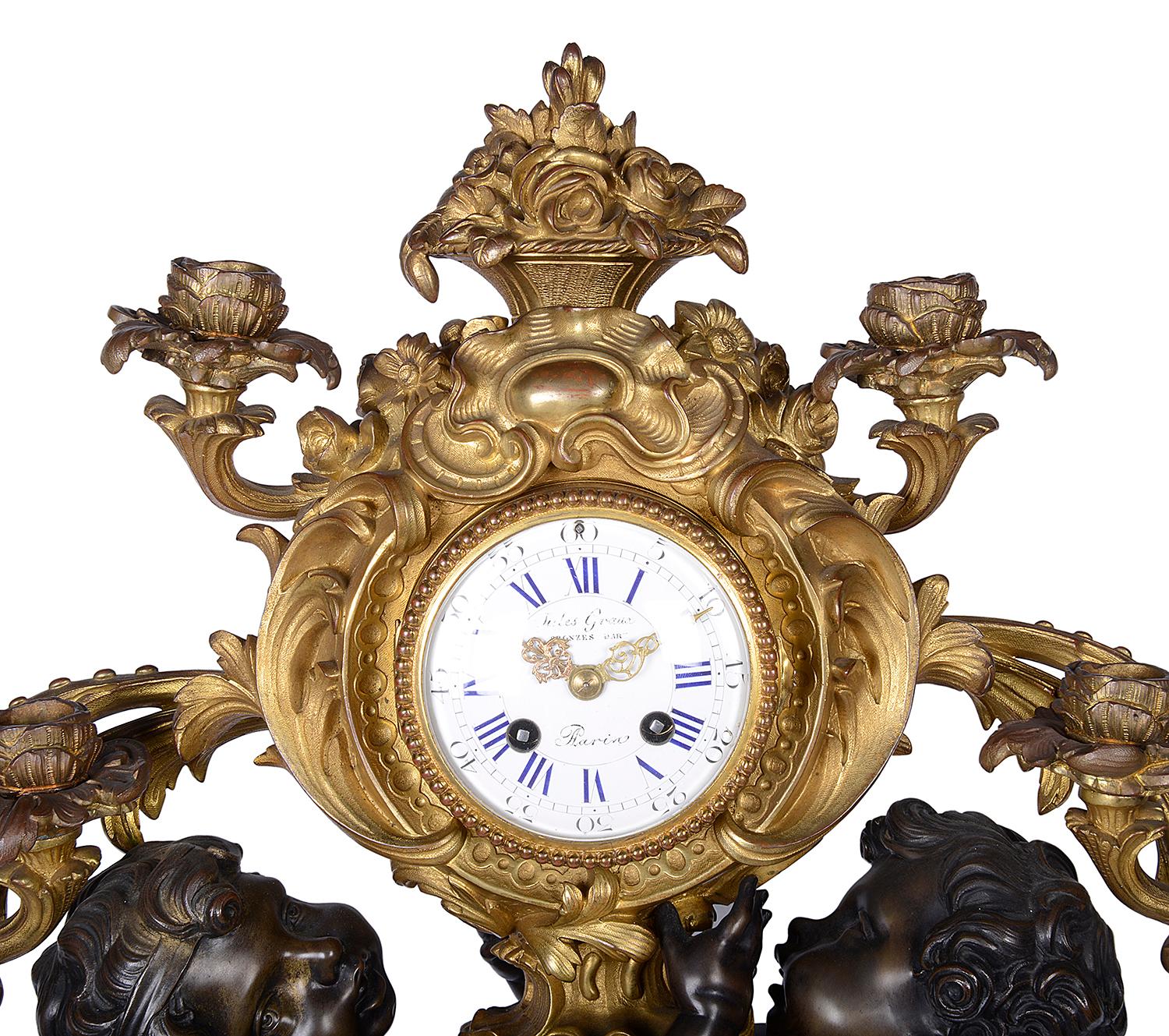 A very impressive 19th century French gilded ormolu and bronze mantel clock, having a pair of bronze putti entwined around the eight day duration chiming clock with four scrolling foliate candelabra and raised on a Rococo style base.