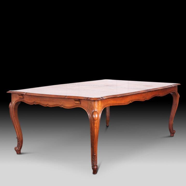 A grandly-scaled 19th century French walnut Louis XV style extending dining table, the shaped plank top opening in the centre to take a large leaf. Shaped apron and standing on well-carved elegant cabriole legs with scrolled feet. Presently there