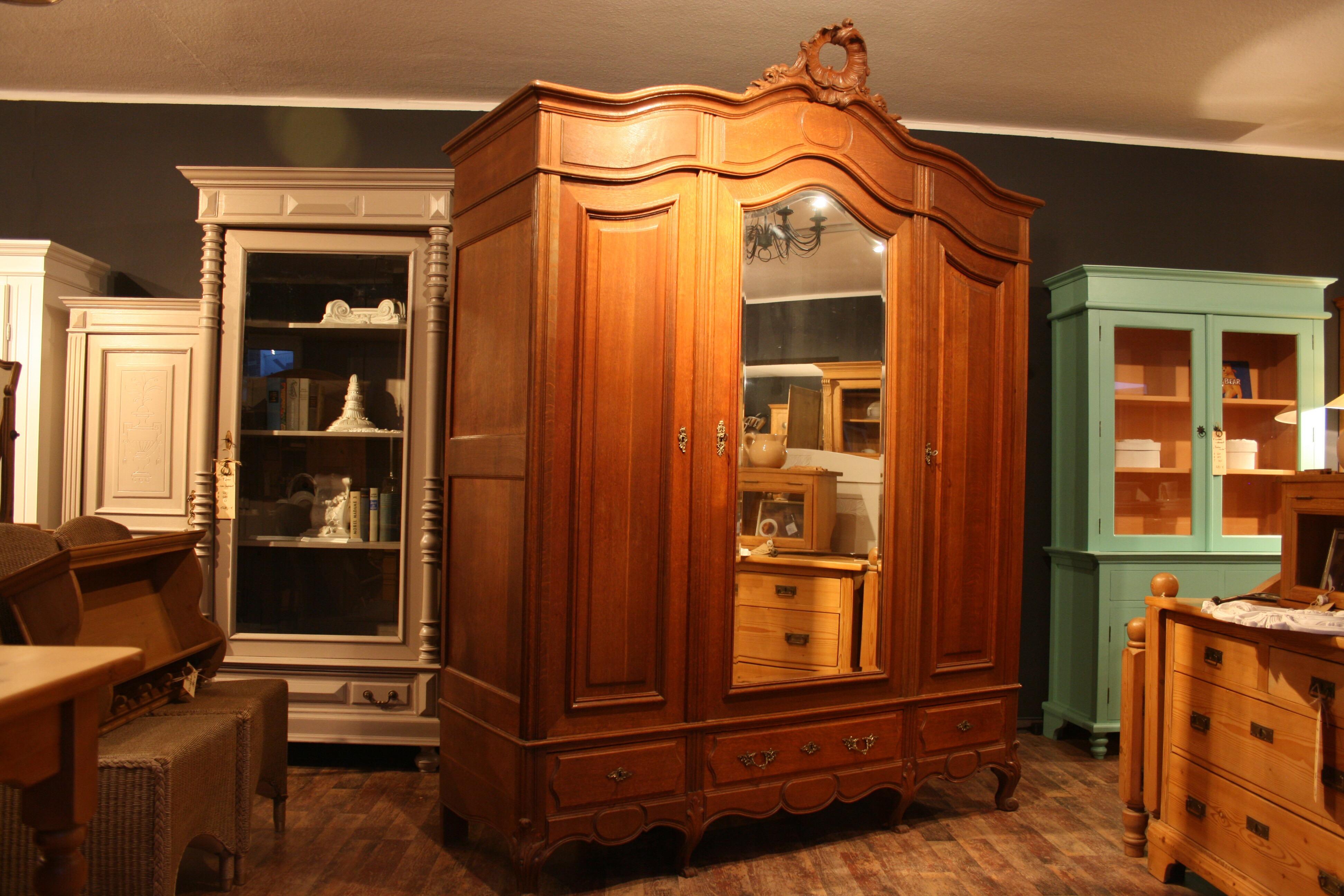 Beautiful large wardrobe in Baroque style solid oak. France, circa 1930. In the middle with a large mirrored door with a polished mirror edge. One door and three drawers in the lower part on the right and left, all with brass fittings. The headboard