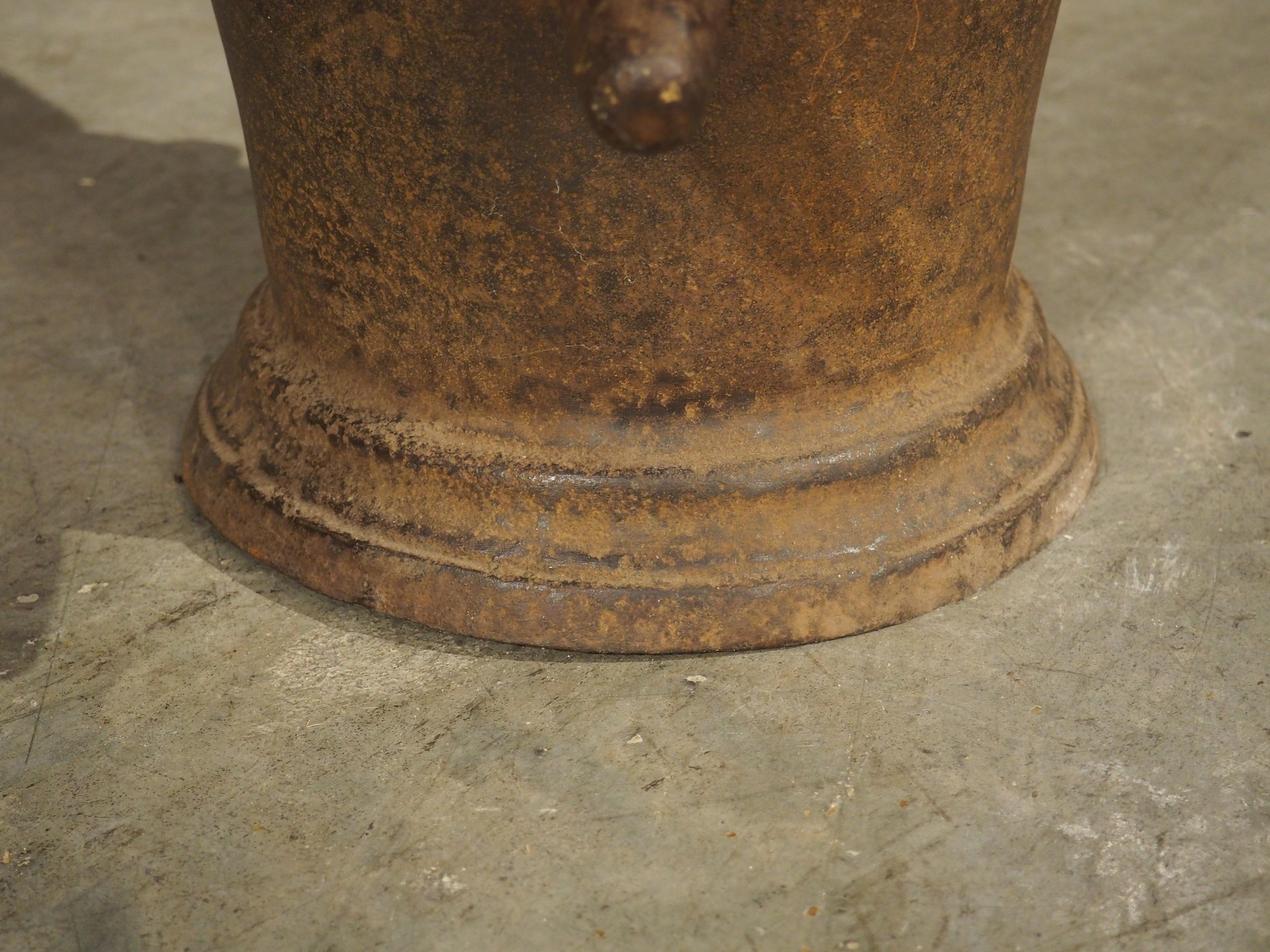 A unique example of the traditional French pharmacy mortar, this cast iron version is from circa 1800 and features a large wooden pestle (16 inches tall with a diameter of 2 ¾) with a lovely honey hue. The brown-colored iron has developed a