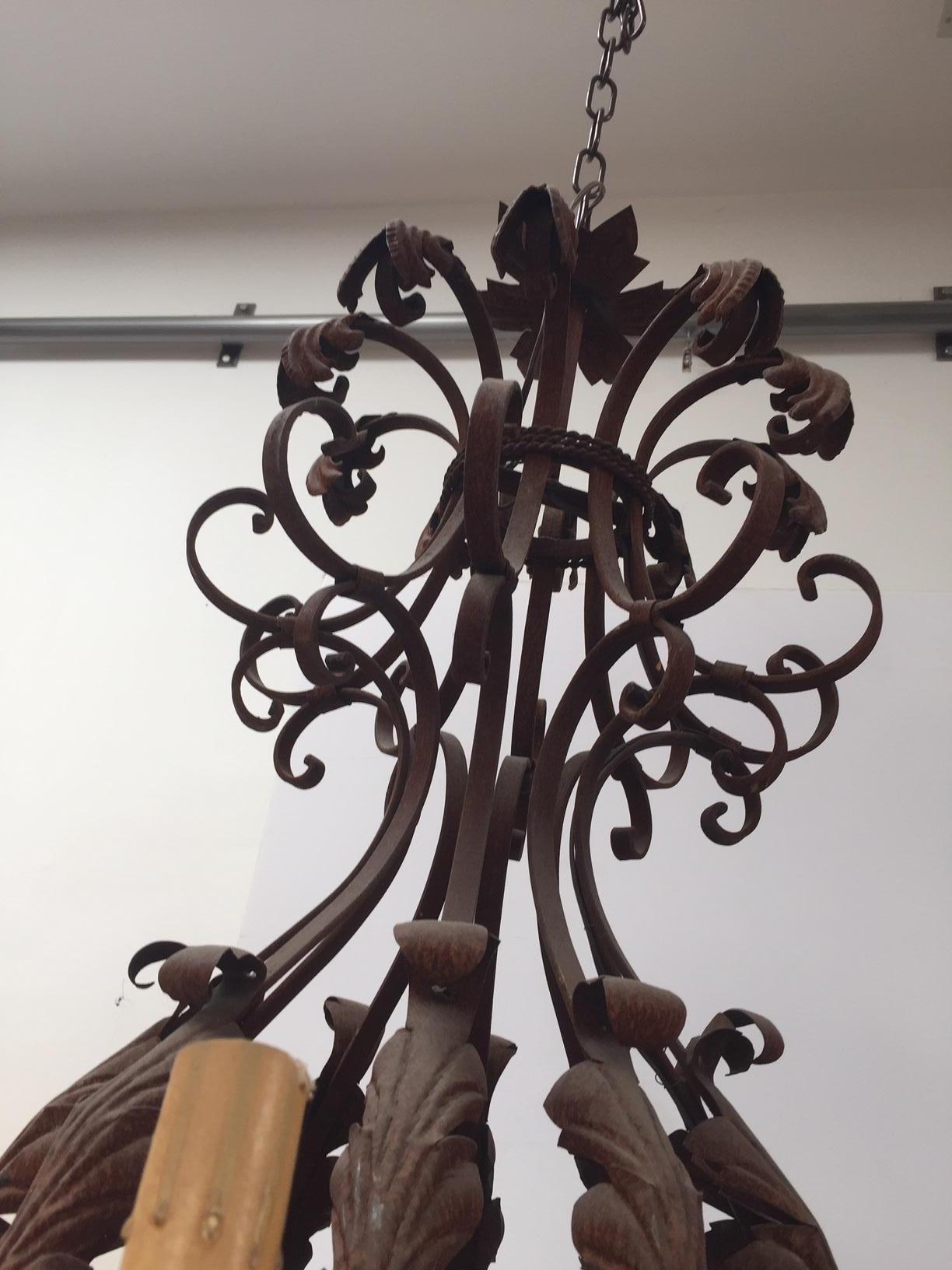 Large French Iron Chandelier. Impressive handcrafted iron chandelier. This piece could be use inside or outside in a French or European Style patio covered area. This unique chandelier is highly decorate with leaves on arms and bobeches wired with