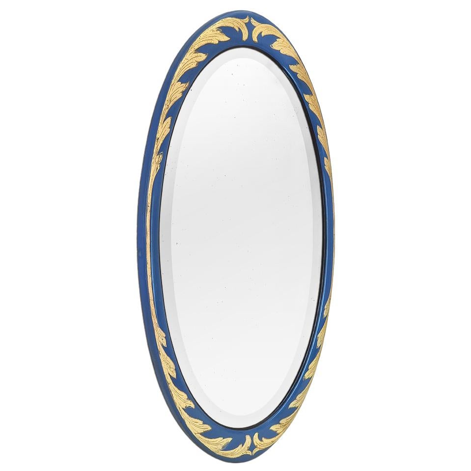 Large French antique mirror, oval shape, Art Deco period, circa 1928. Blue color frame is decorated with stylized foliages, overlaid with gold leaf, and highlighted by a black border that edges the beveled glass mirror. Frame width: 4 cm & 7 cm/
