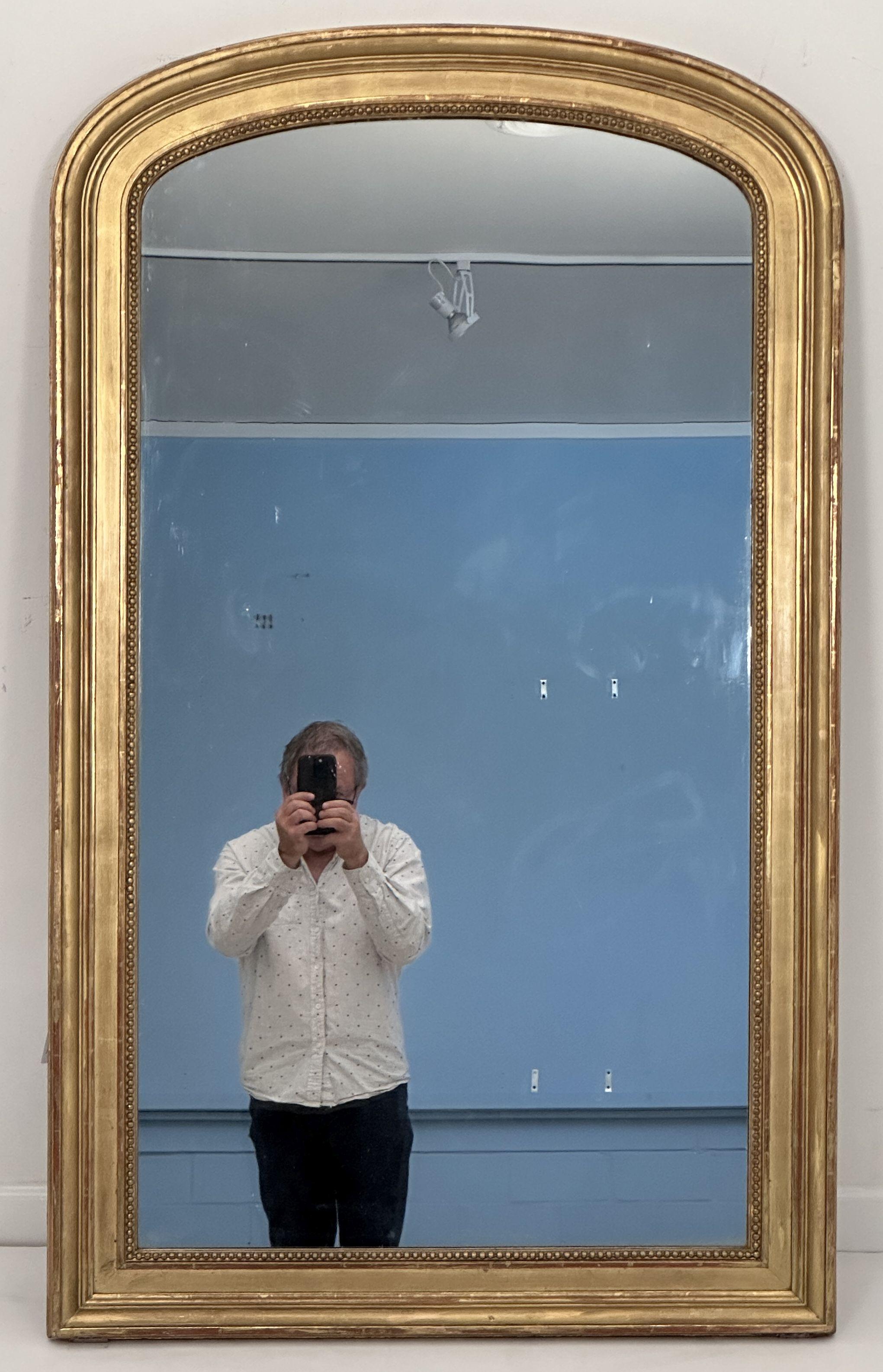 Raffinata specchiera francese da parete o da sala degli inizi del XIX secolo, caratterizzata da un bordo sagomato in rilievo con una bella foglia d'oro patinata e da una serie di perline di gesso dorato incastonate nella lastra originale dello