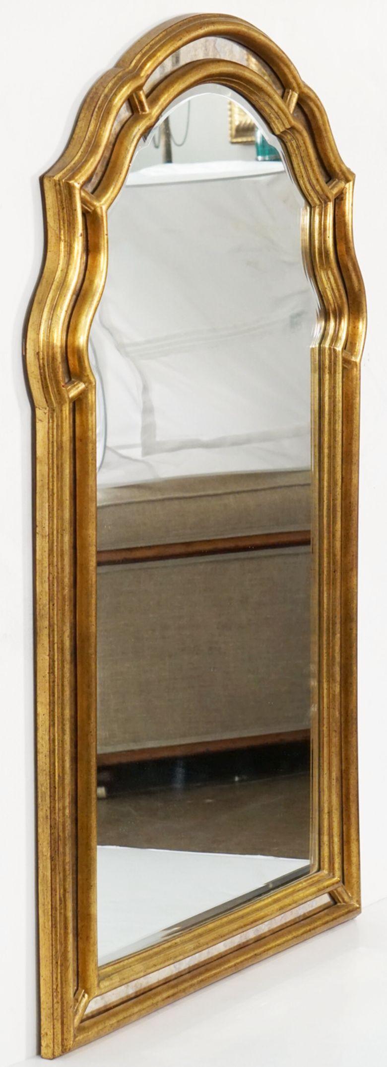 A large vintage French gilt wall mirror in the Hollywood Regency style - featuring a serpentine arch-top and segmented mirror gilt frame.