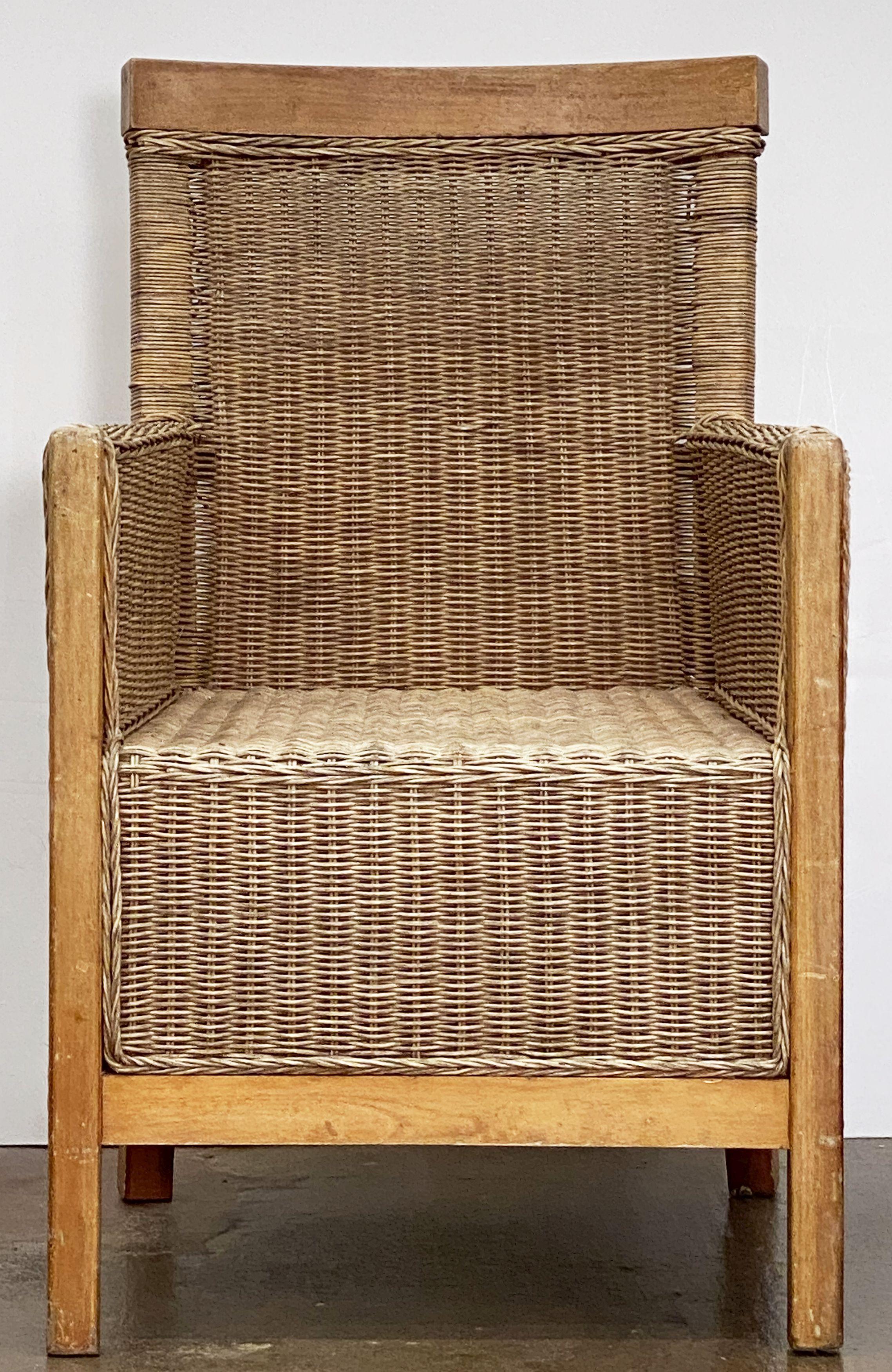 A fine large French armchair or lounge chair of woven wicker cane and beechwood featuring a comfortable back and seat and a sturdy modern design.

Two available.