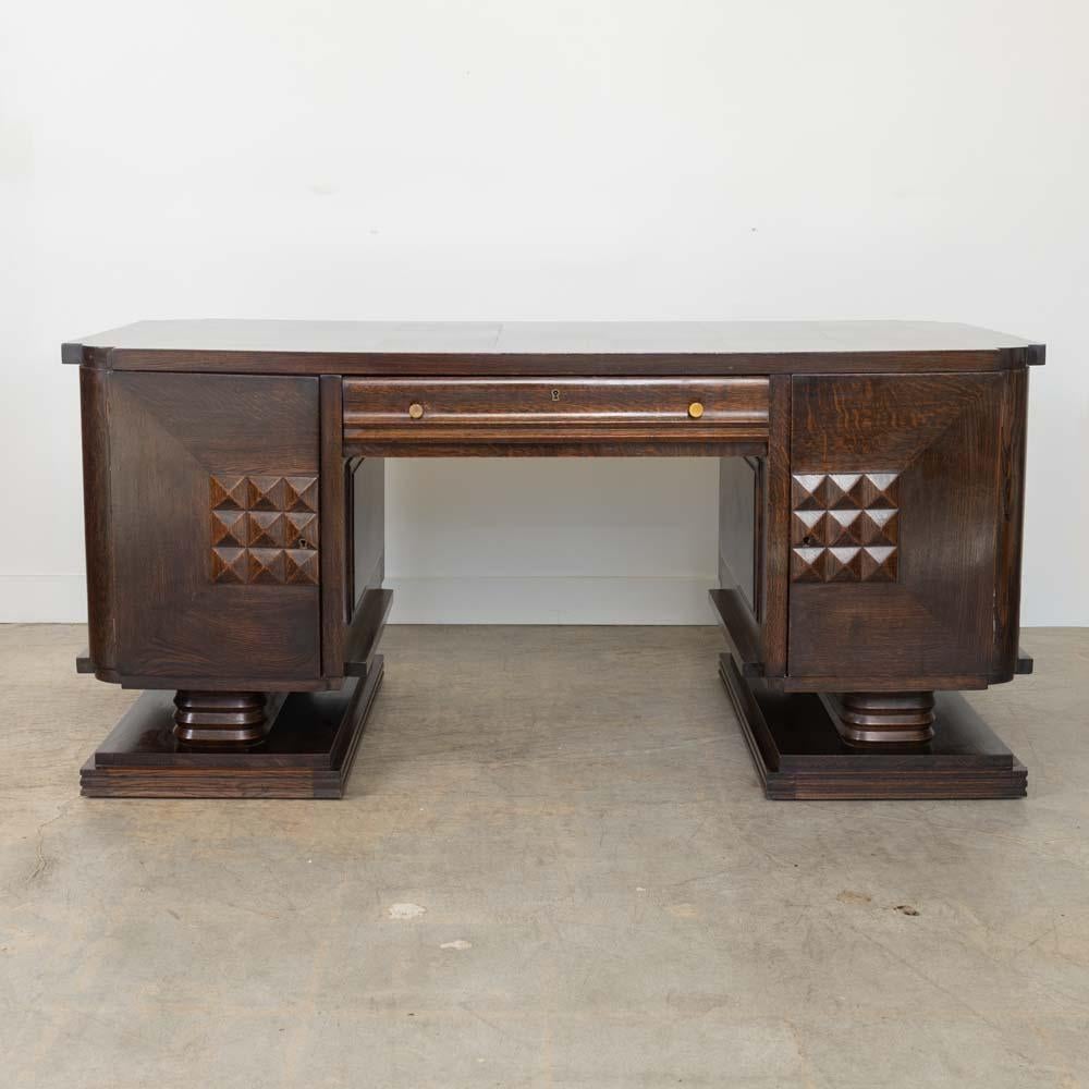 Bellissima scrivania in legno Art Déco di Charles Dudouyt, Francia, anni '30. Piano rettangolare in parquet con gambe in legno intricatamente intagliate su una base a piedistallo. Due ante su ciascun lato si aprono su tre cassetti con un cassetto