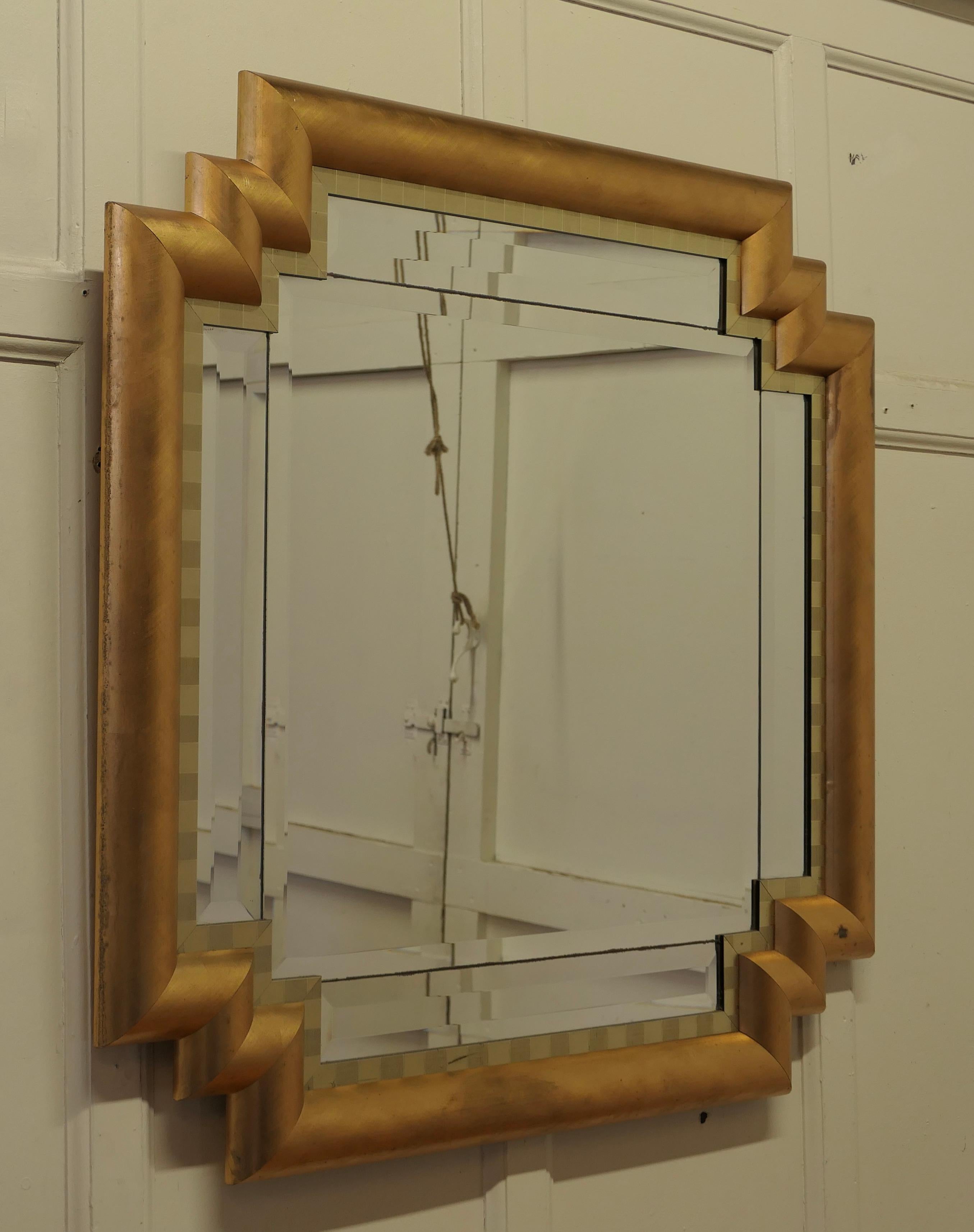 Large French Art Deco Odeon Style Gilt Mirror

The Art Deco frame has an odeon style stepped corner and a 4” wide D shaped Gilt frame 
This is a lovely and a fine quality piece, just like a cushion Mirror the central bevelled glass is set with