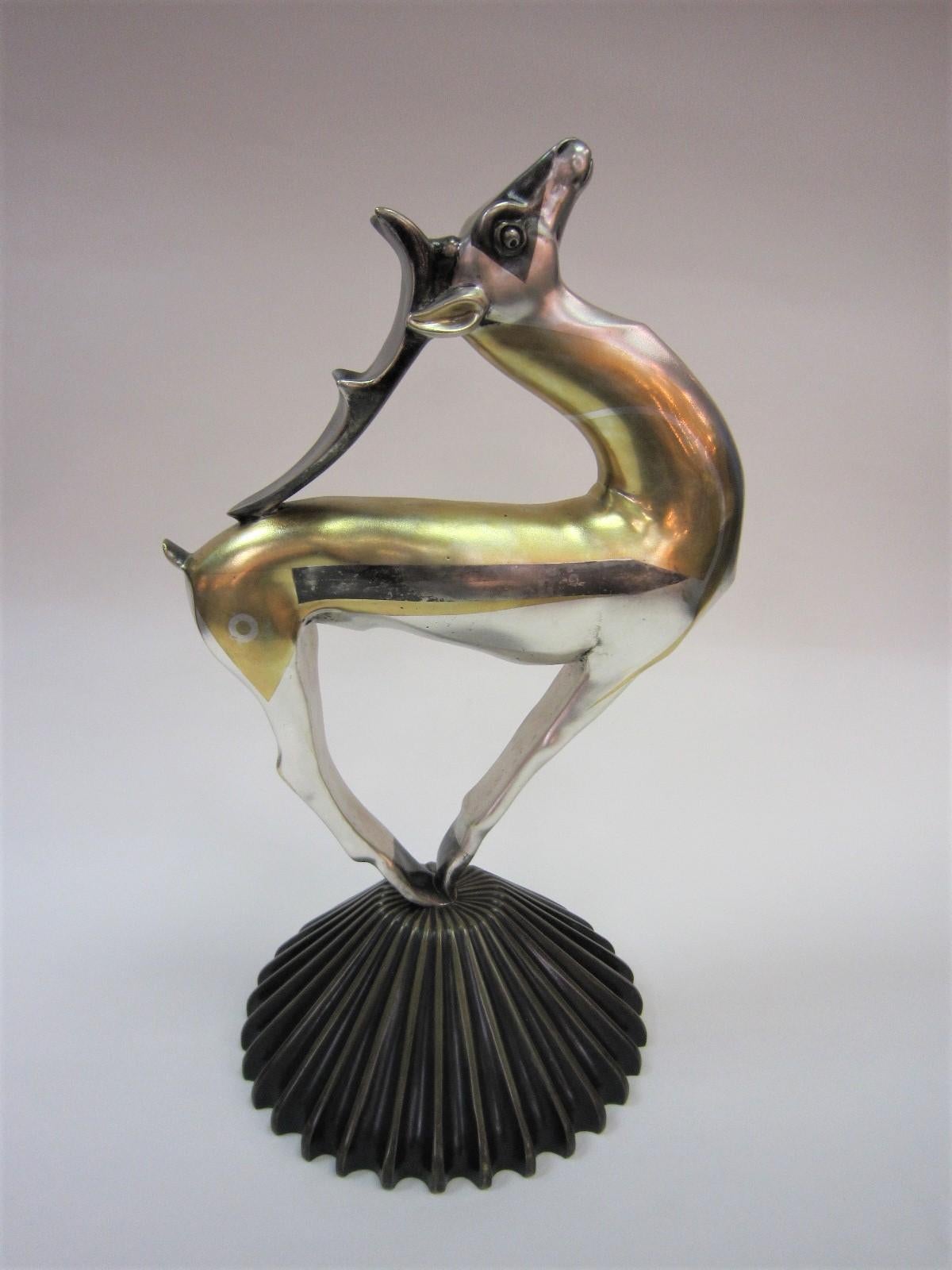 A large French Art Deco bronze sculpture of a gazelle in bronze with parcel gilt and silver on fluted self base.
 This rare and artistic damascened, non inlaid finish epitomizes the grace and elegance of the animal featuring slender legs, a level