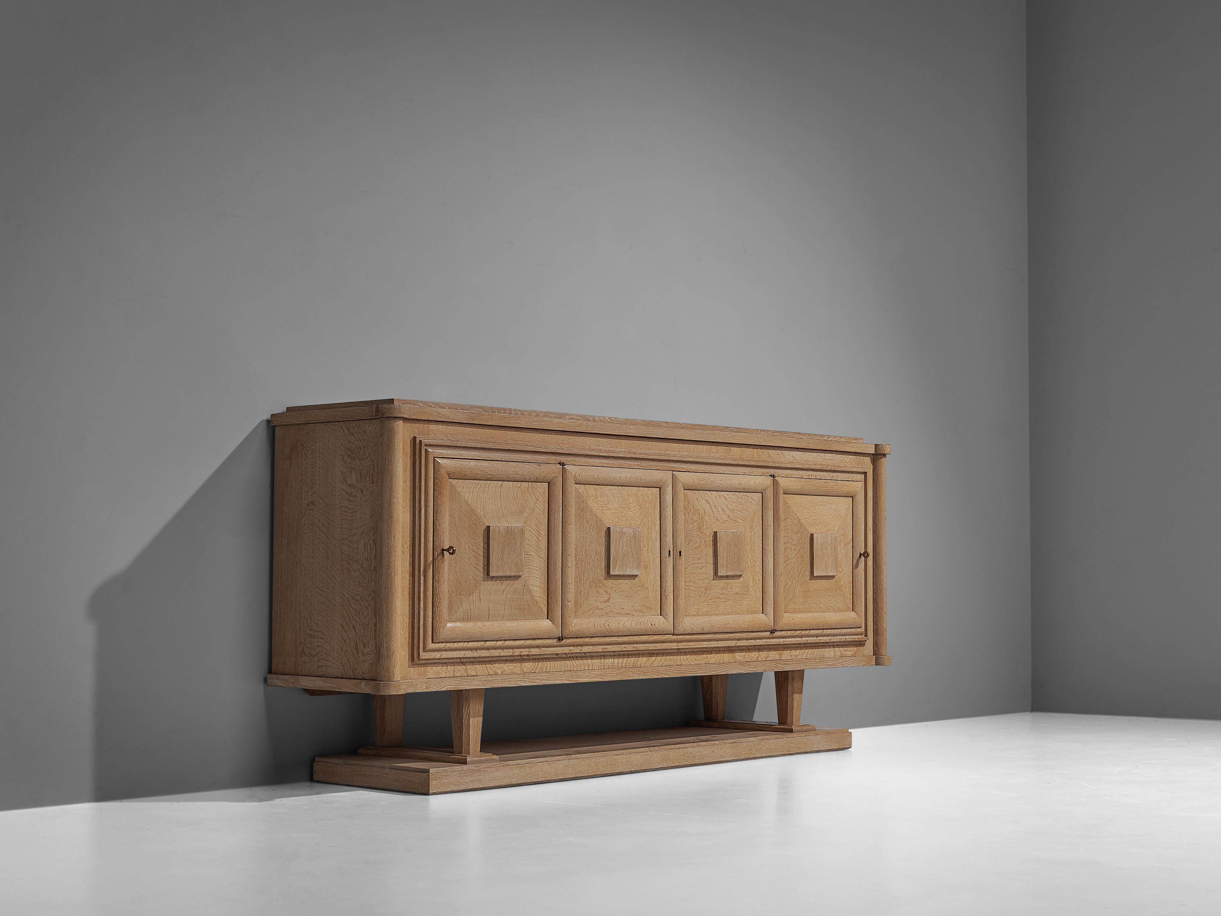 Sideboard, oak, France 1930s. 

Large credenza in oak. The sideboard has four doors, all with beautifully designed wooden graphical patterns. The diagonal lines with added squares and a frame emphasize the three-dimensional character of the front.