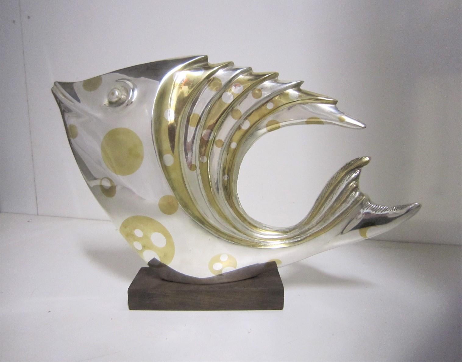 Un grand et impressionnant poisson en argent et bronze doré à la feuille attribué à Marie Louise Simard.
Cette élégante sculpture d'art d'un poisson exotique stylisé, semblable à un discus, un poisson lune ou un poisson épineux argenté, flotte sans