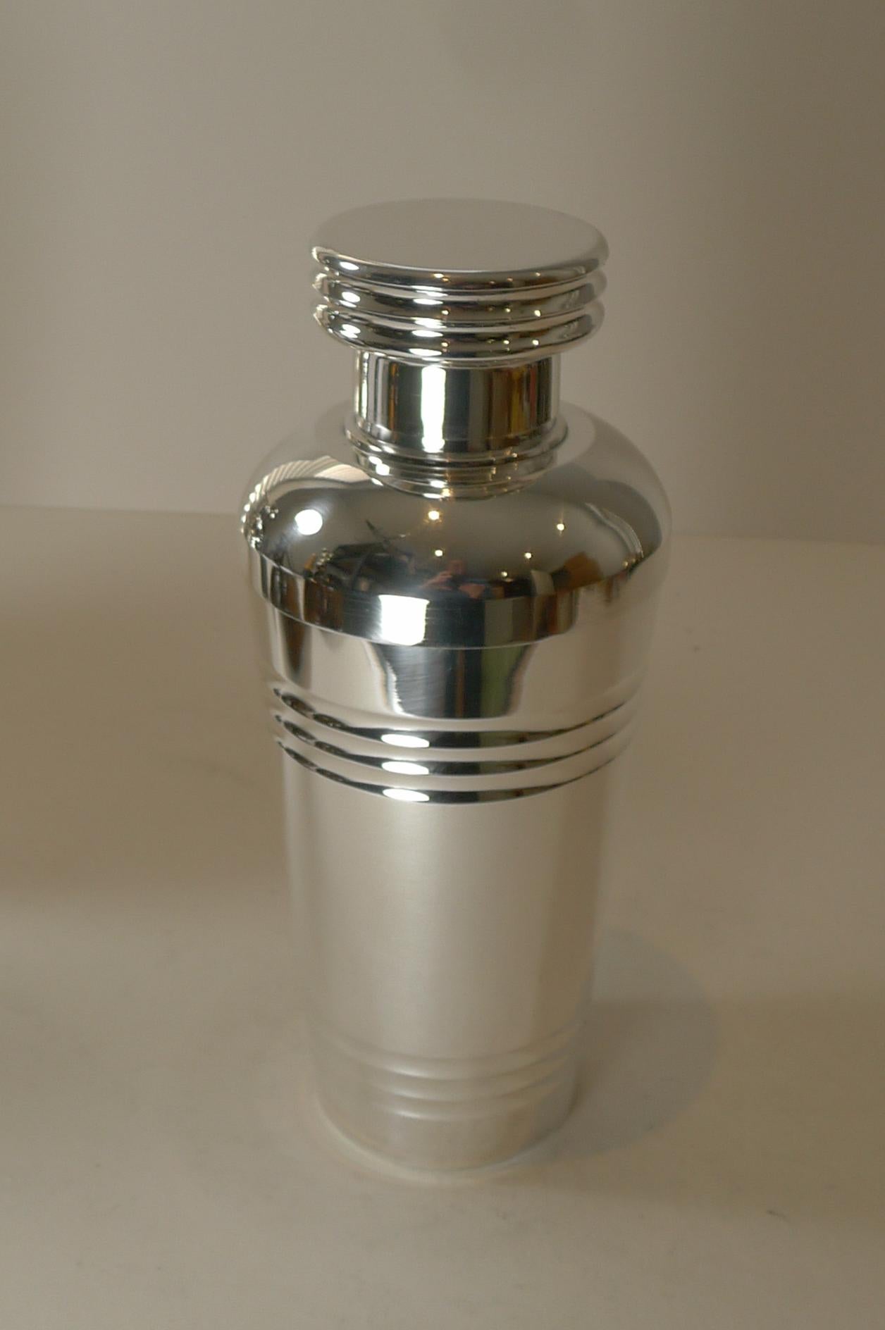 A very strong shape and design was adopted to create this large Art Deco Cocktail shaker dating to c.1925.

Our silversmith has professionally cleaned and polished it to create a piece in excellent condition. The pull off top retains it's original