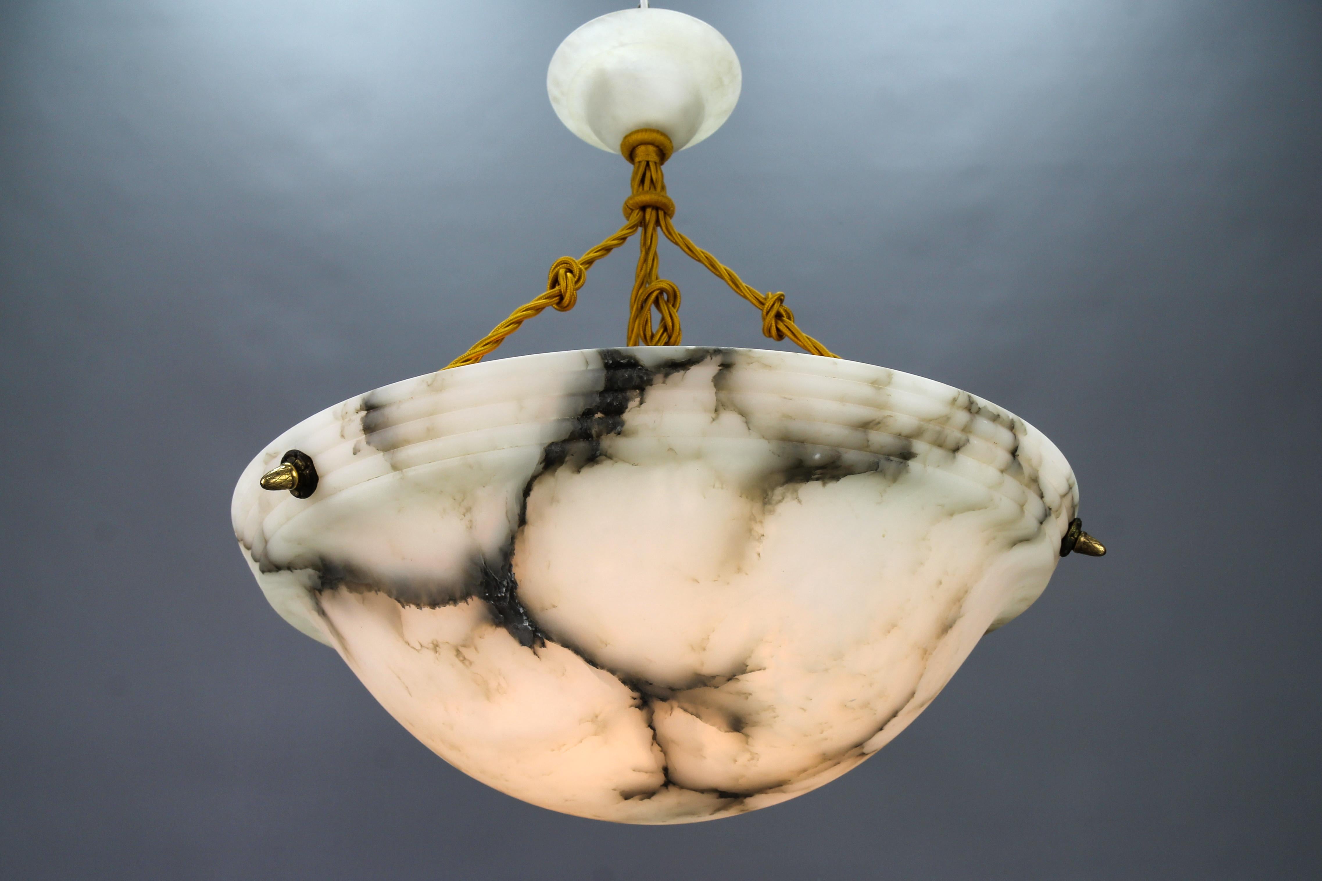 Large French Art Deco white and black alabaster pendant light fixture.
Gorgeous and large French alabaster pendant ceiling light fixture from the 1920s. Beautifully veined and masterfully carved one-piece white alabaster bowl suspended by three