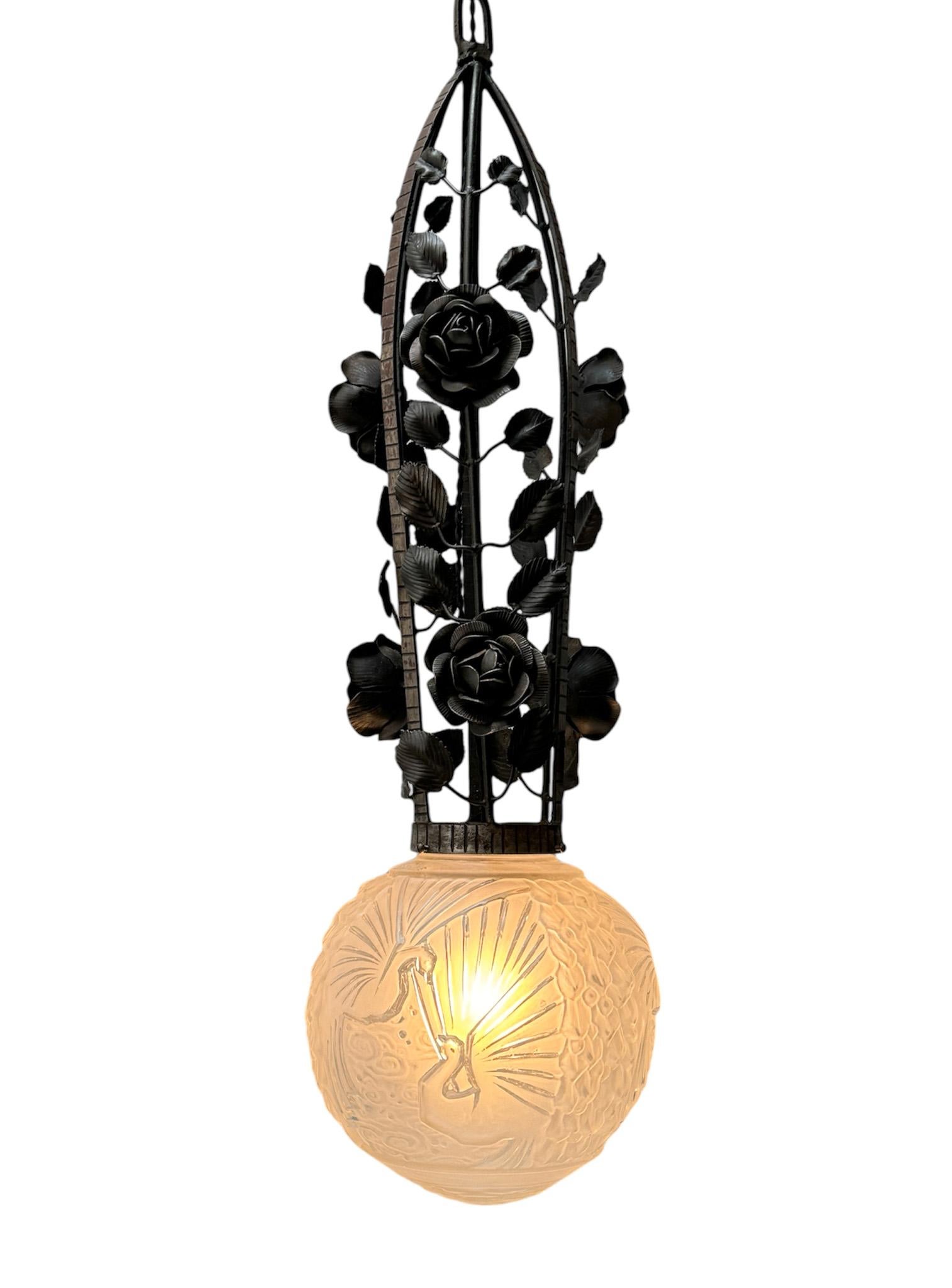 Magnificent and rare Art Deco pendant light.
Design by Muller Frères Luneville.
Striking French design from the 1930s.
Original black lacquered wrought iron frame with decorative elements.
The original frost glass shade is decorated with peacocks