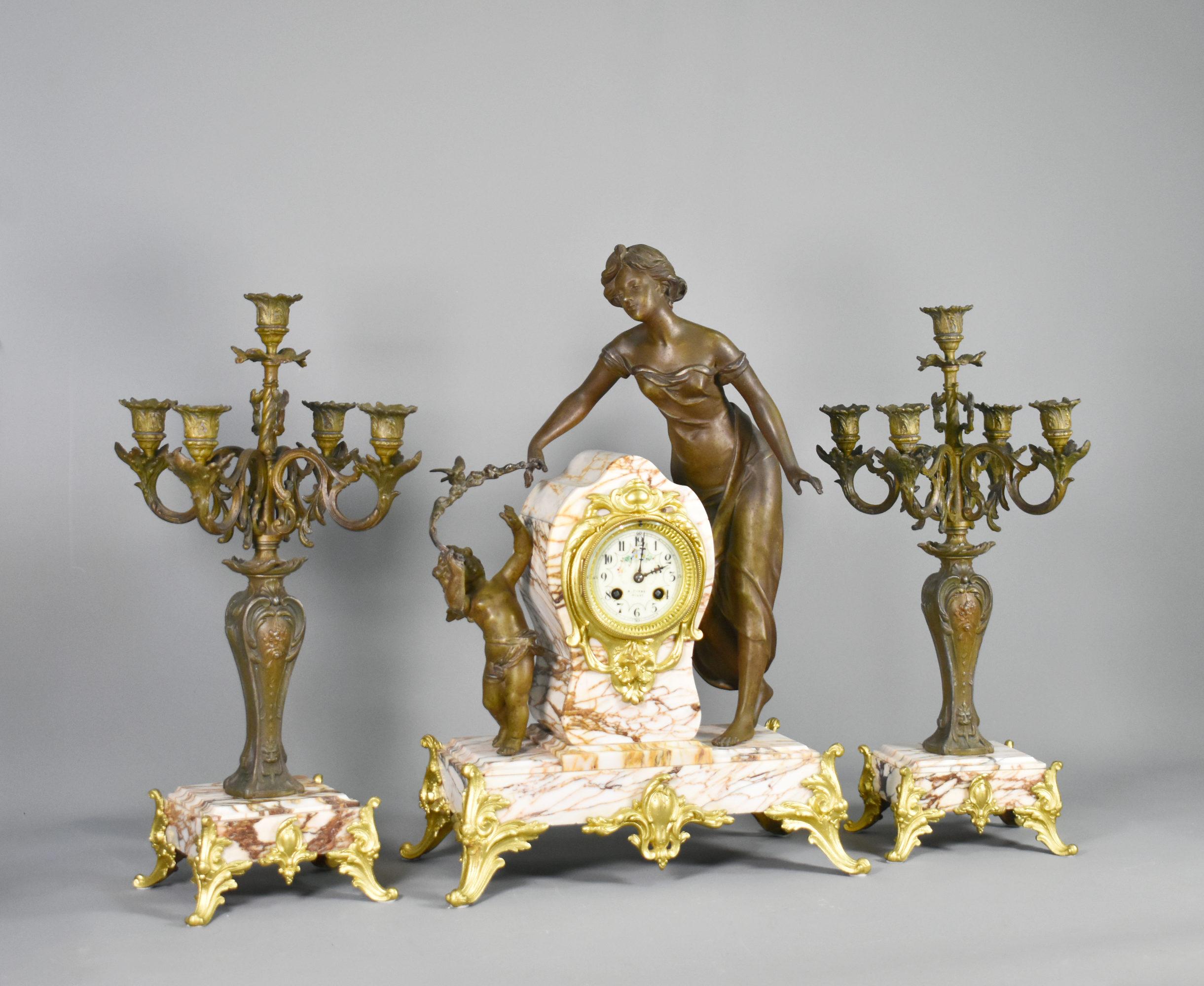 Large French Art Nouveau Mantel Clock and Garniture 

This impressive clock set features a woman and child holding a floral branch with a bird perched above. 

A striking centrepiece, the figures are cast in bronzed spelter and stand on a