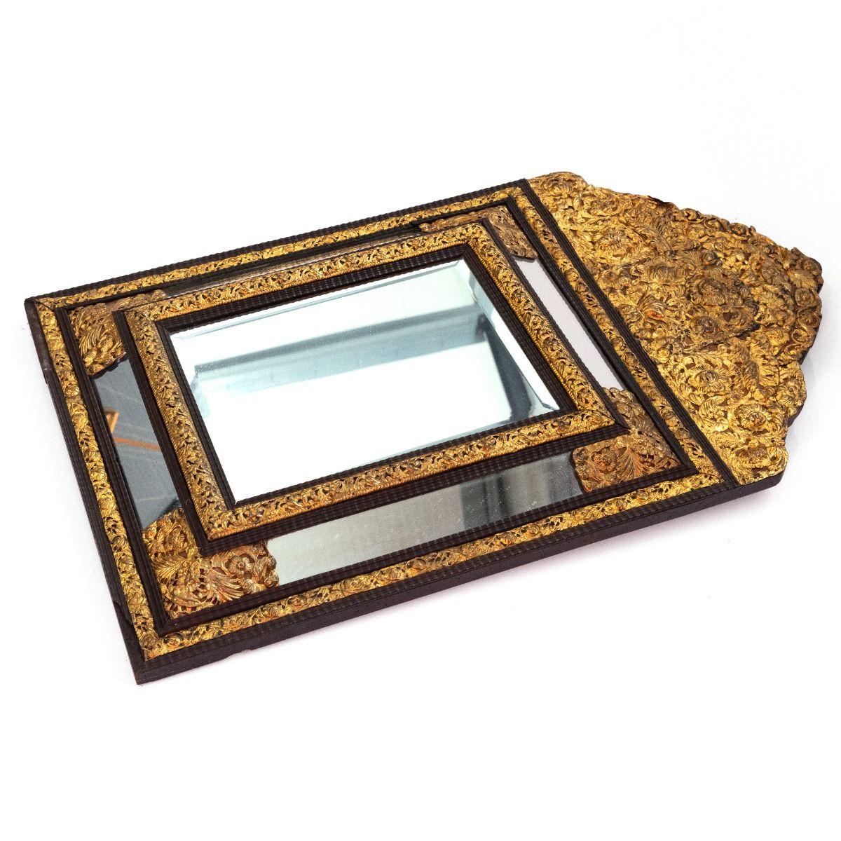 Specchio francese decorativo con vetro centrale smussato.
Adornato con motivi floreali e fogliati in ottone dorato finemente cesellati e incisi con dovizia di particolari.
Incorniciato da legno ebanizzato con un profilo sottilmente curvo, che crea