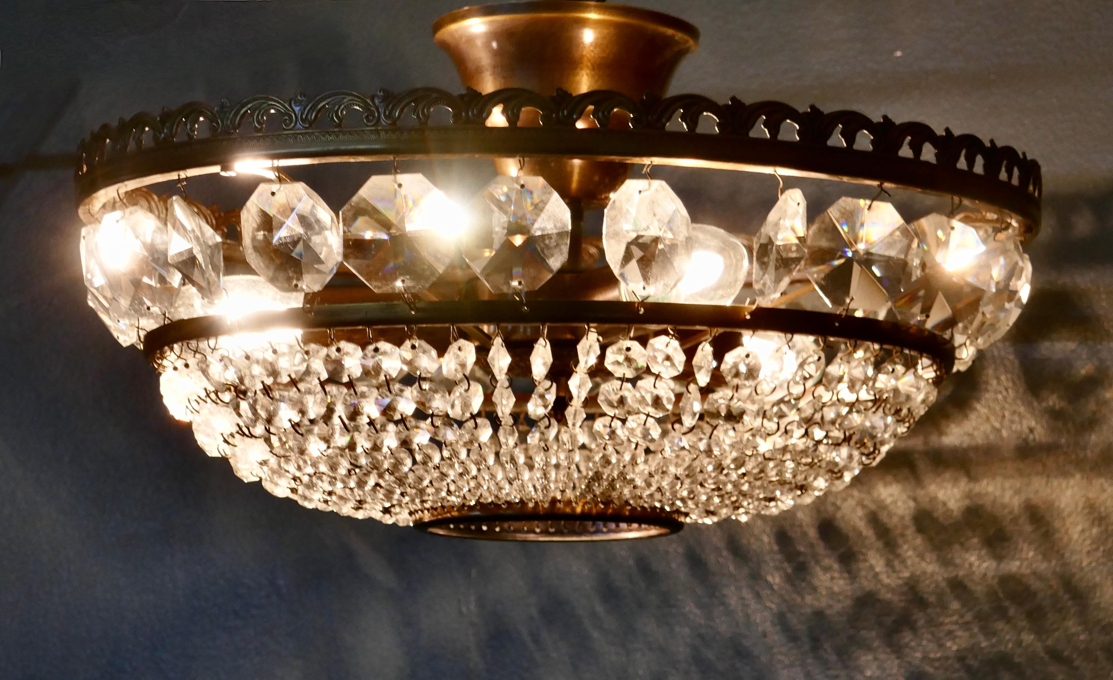 Large French basket crystal chandelier.

This is not a very deep chandelier so a good one if the ceilings are not very high, it has a decorative brass frame.

The hanging basket is suspended from a wide crown filled with large pendants, this