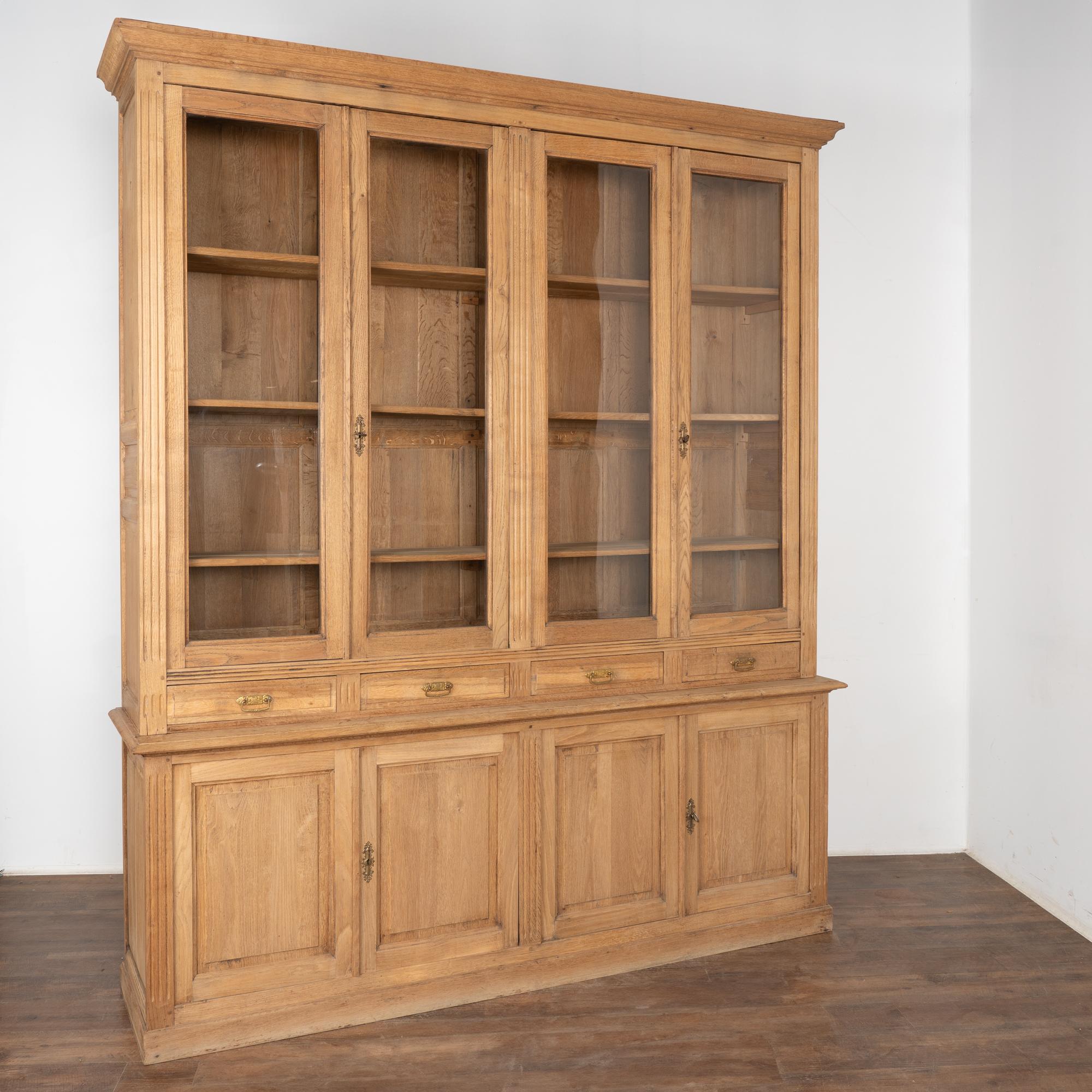 This impressive oak bookcase has four upper glass paneled cabinet doors and four panel cabinet doors below.
The oak has been bleached creating a fresh, lighter finish for today's modern home.
This large display cabinet is made in two sections, upper