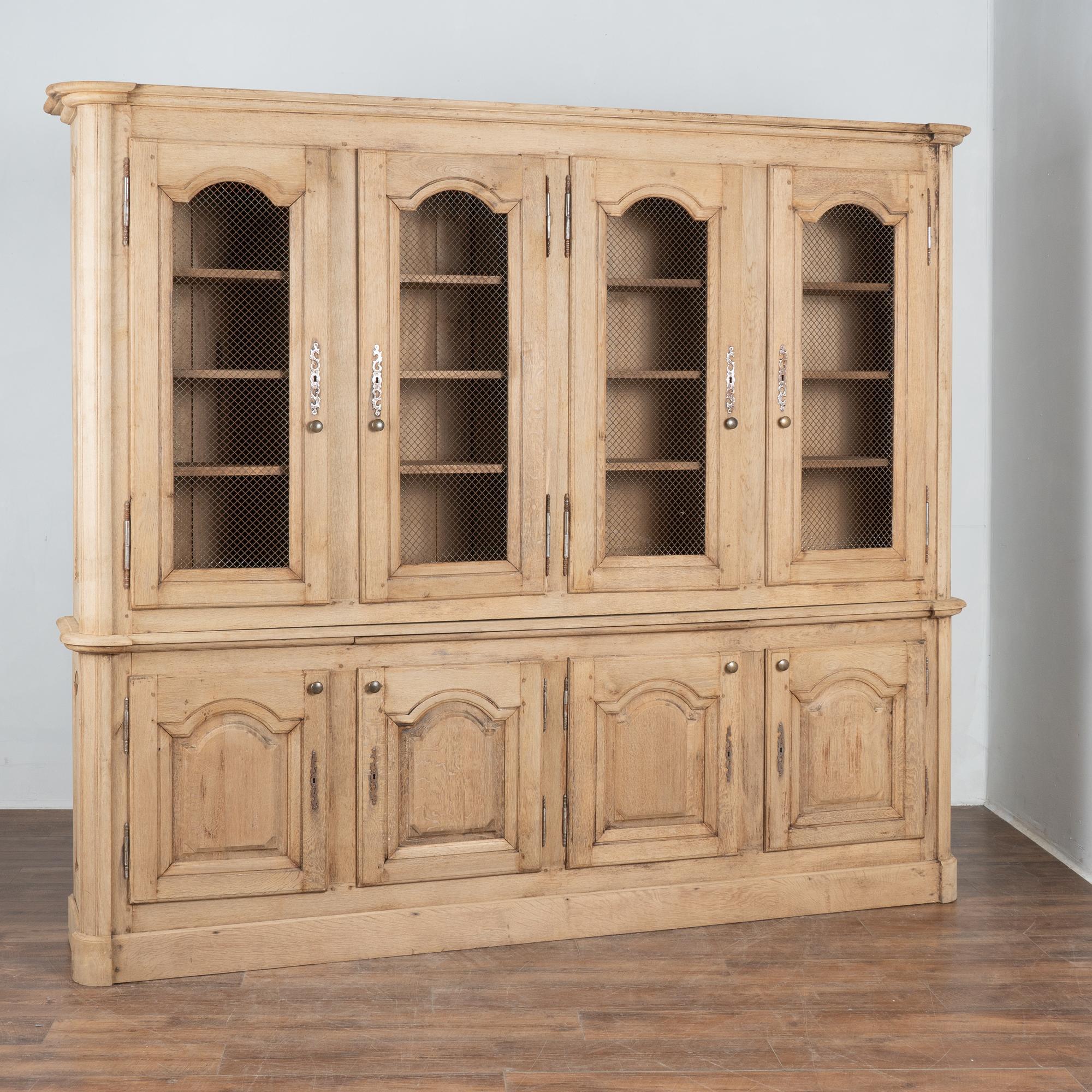 Questa imponente vetrina in Oak è dotata di quattro ante superiori e quattro ante inferiori.
Gli oggetti esposti nell'armadio superiore sono facilmente visibili attraverso il filo di ferro che conferisce a questo armadio largo 8,5' e alto 7'