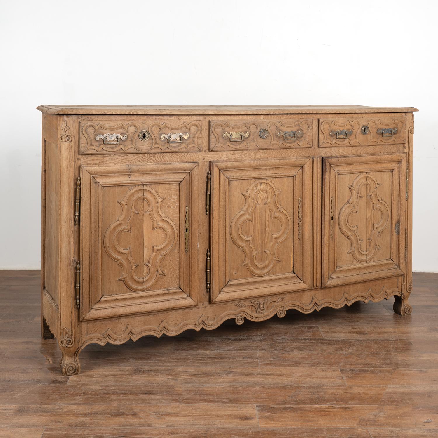 It is the lovely carved details and heavily paneled doors that draws one to this French oak sideboard while the bleached finish gives it a fresh and welcoming look for today's modern home and shows off the wonderful grain.
The attractive scalloped