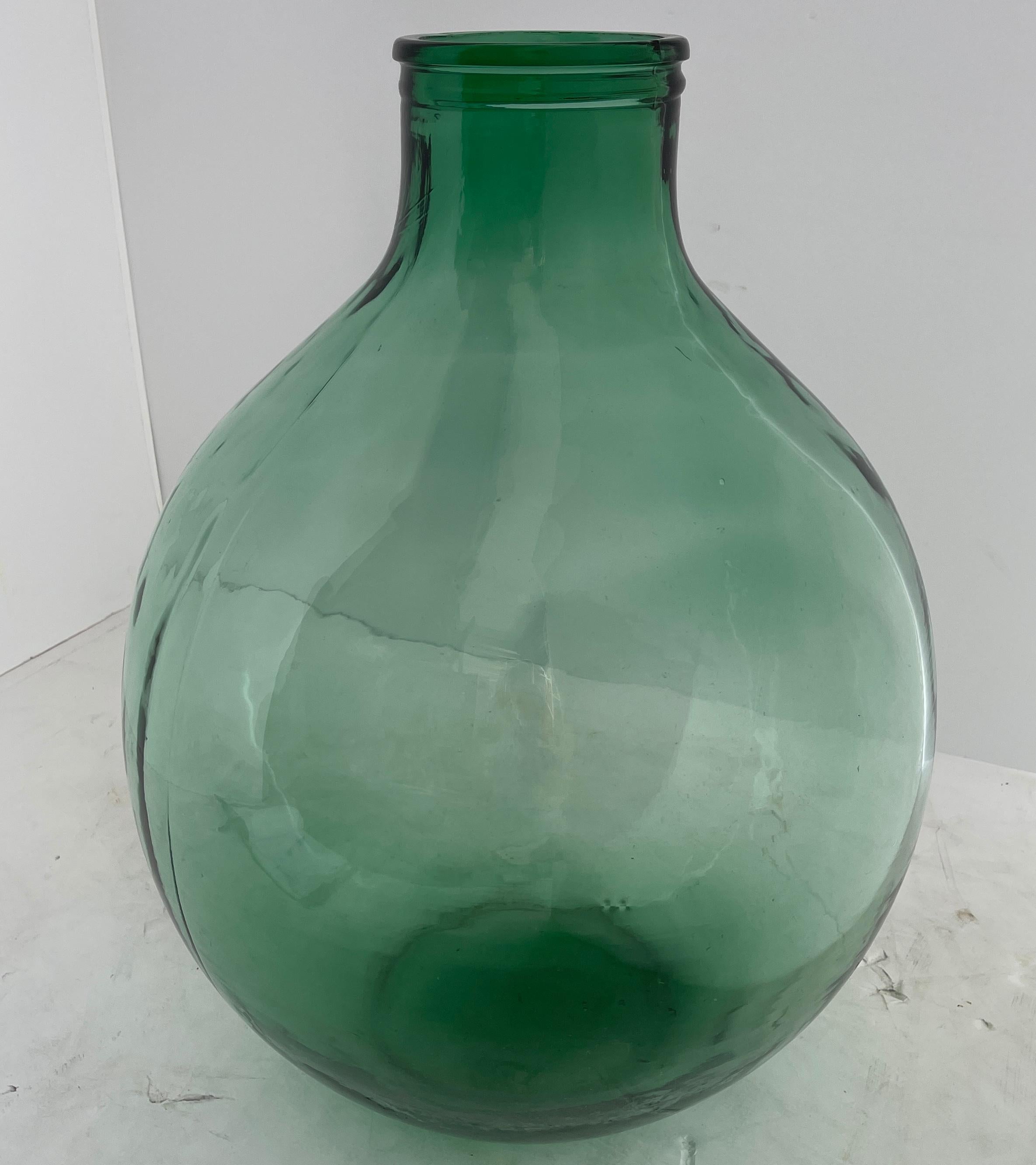 Early 1900 hundreds blown glass demijohn bottle, France.
This huge outstanding vessel is tall and sturdy. It's large mouth allows the bottle to hold a large bundle of flowers as well as an abundance of liquids. The green glass is a wonderful