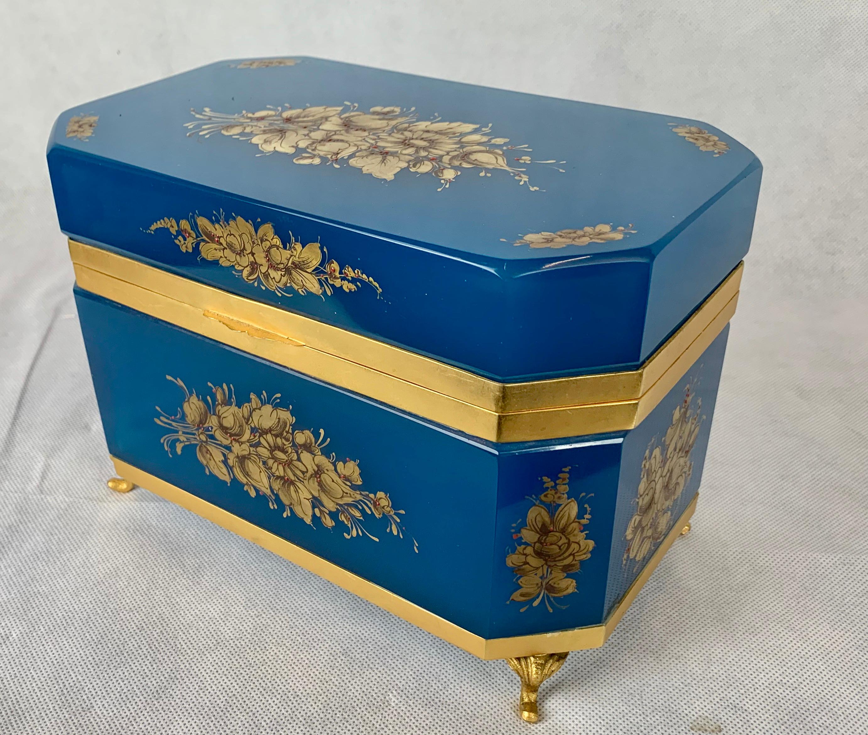Large French blue Opaline glass box.  Hand painted with gilt floral sprays. Hinged bronze doré frame with thumb catch and cabriole feet. The rectangular shape has cut corners and gilt decoration on all sides.
The opaline box is in beautiful