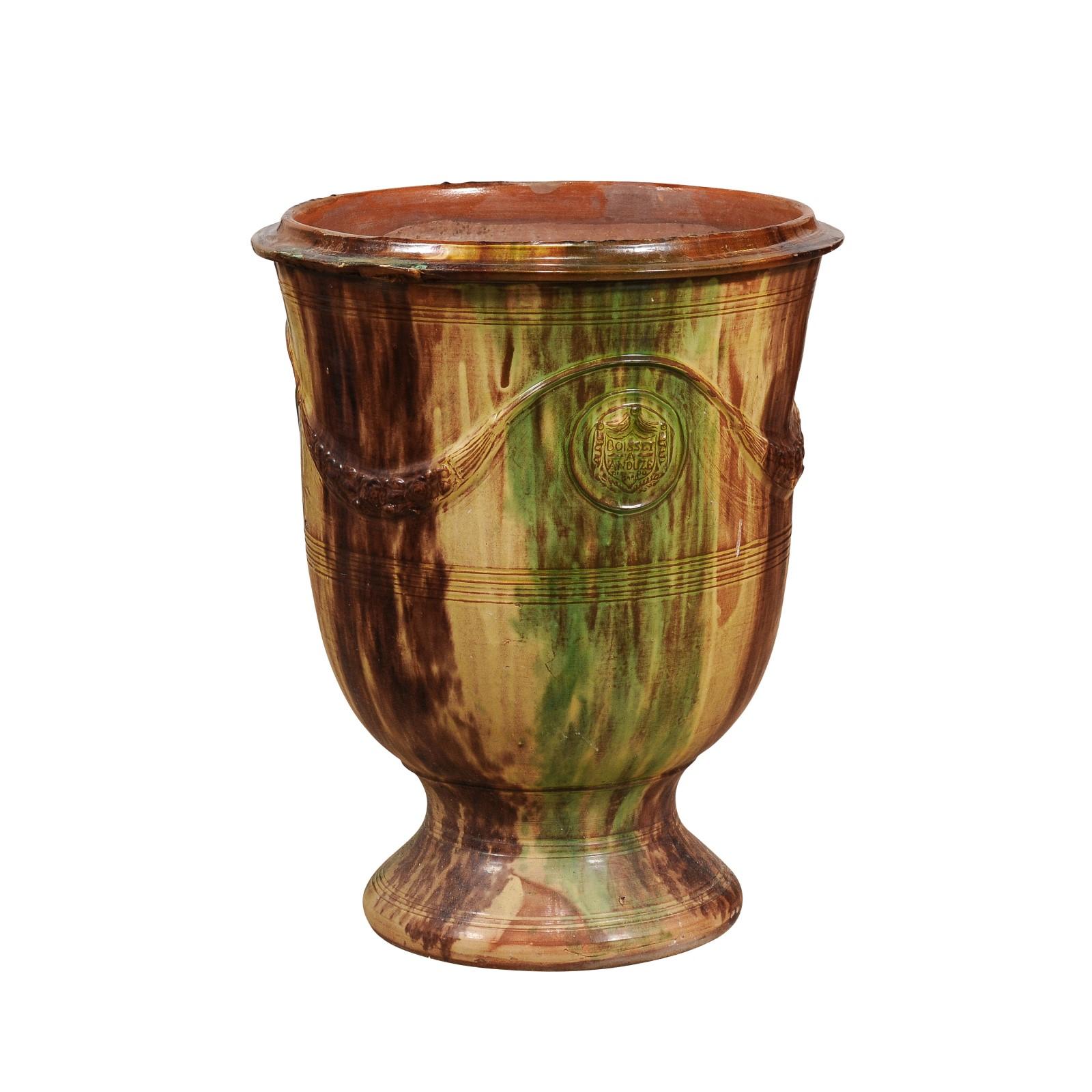 A French Les Enfants de Boisset brown and green glazed Anduze jar from circa 2001 with swags and crests. This French Les Enfants de Boisset Anduze jar captures the essence of traditional craftsmanship with its elegant brown, soft yellow and green