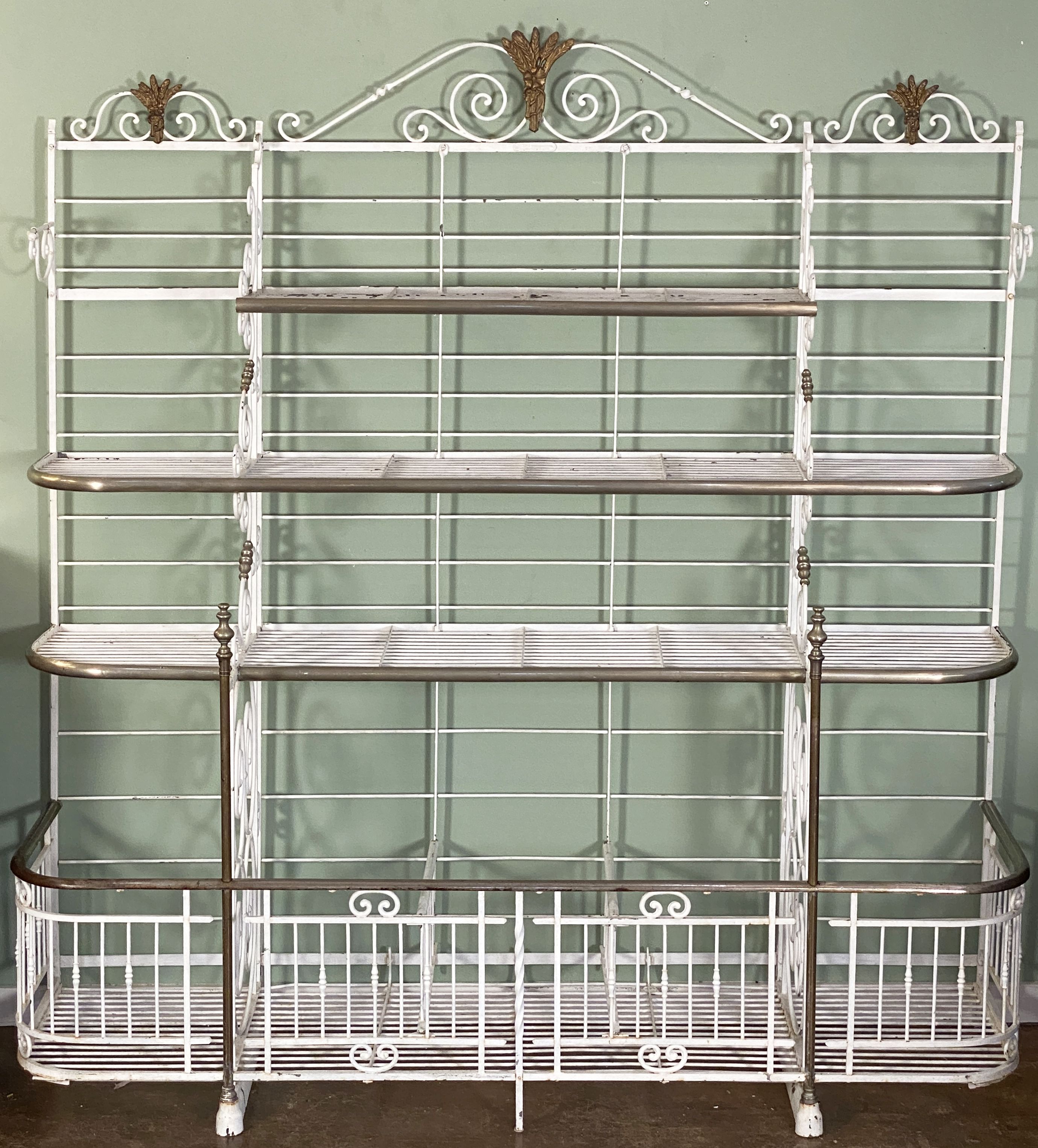 A large French baker's rack boulangerie or patisserie display stand of painted wrought iron with decorative brass and nickel trim - featuring a beautiful frame with scrolled dividing panels, topped with finials and detailed gilded sheaves of wheat,
