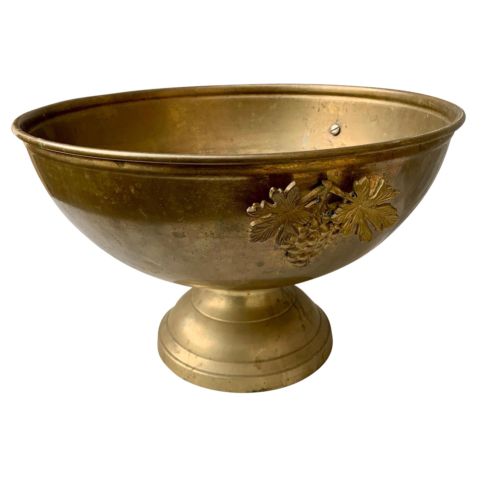 A large vintage brass footed champagne bucket from the early part of the 20th Century. This French wine-champagne cooler is decorated with grapes and grape leaves and has kept its old patina and elegance through the years. This large cooler can