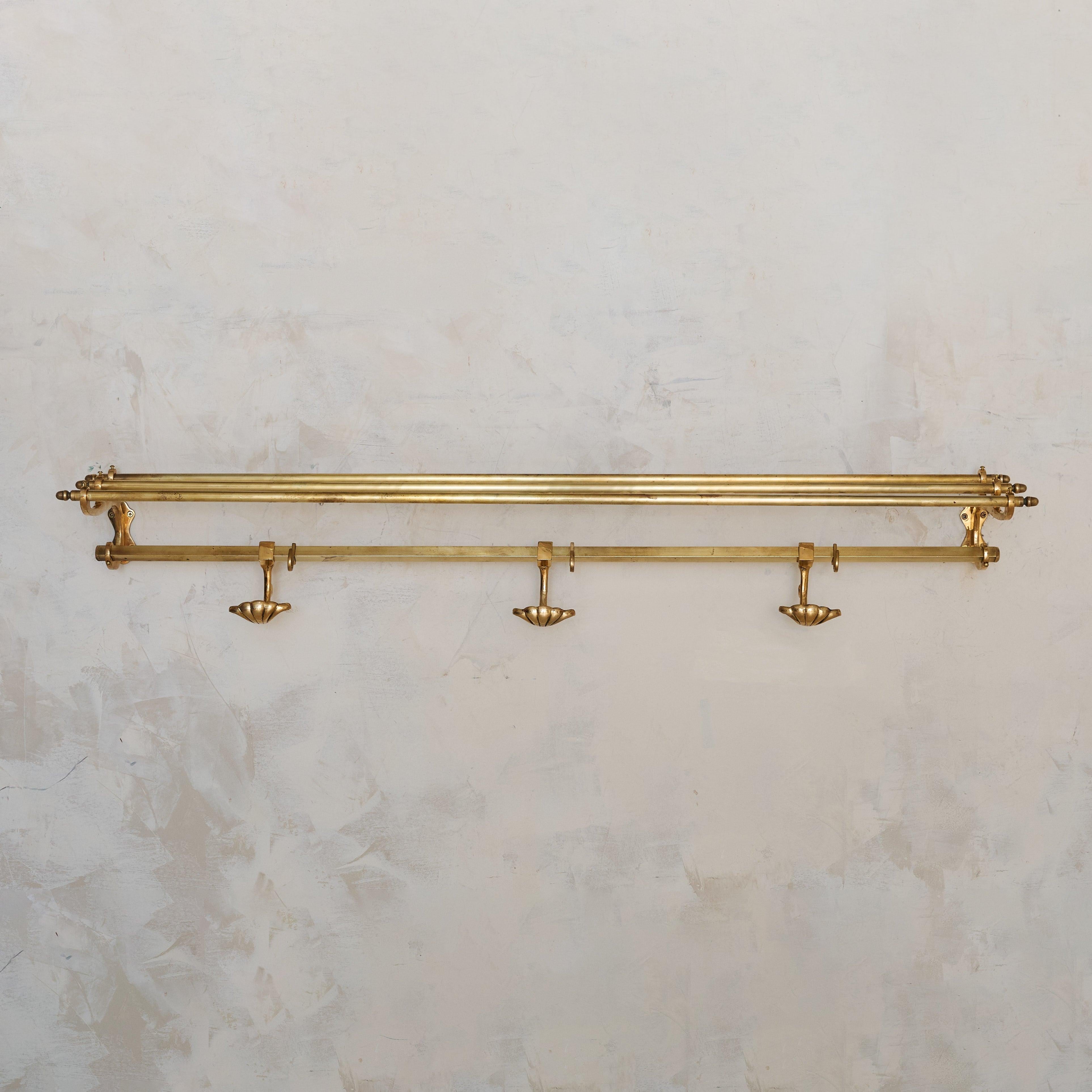 Un appendiabiti da parete francese degli anni '70, definito dalla sua forma elegante e minimalista. Realizzato in ottone, il pezzo presenta un ripiano a doppio binario per riporre cappelli o indumenti piegati, completato da una fila di ganci