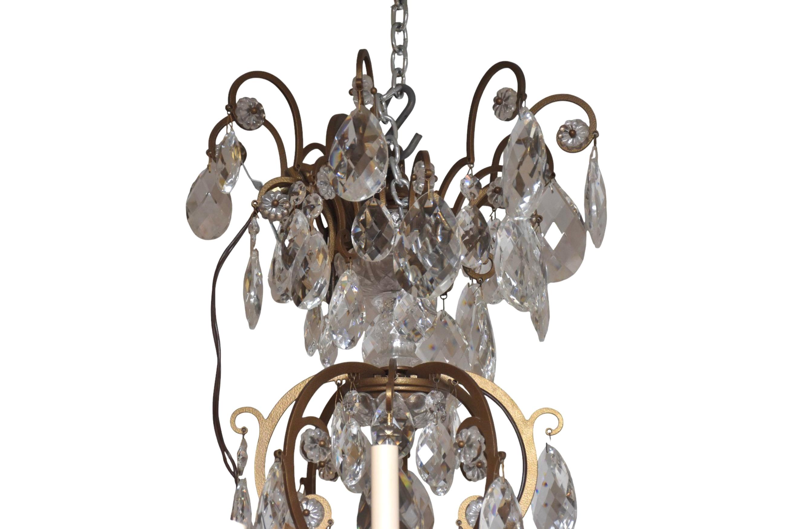 Large French Two-tier Gilt-Bronze and Crystal French Chandelier. Chandelier features a gracefully scrolled gilt-bronze frame adorned with an opulent cascade of hand-cut crystal prisms and pendants, reflecting light with dazzling effect. Each of the