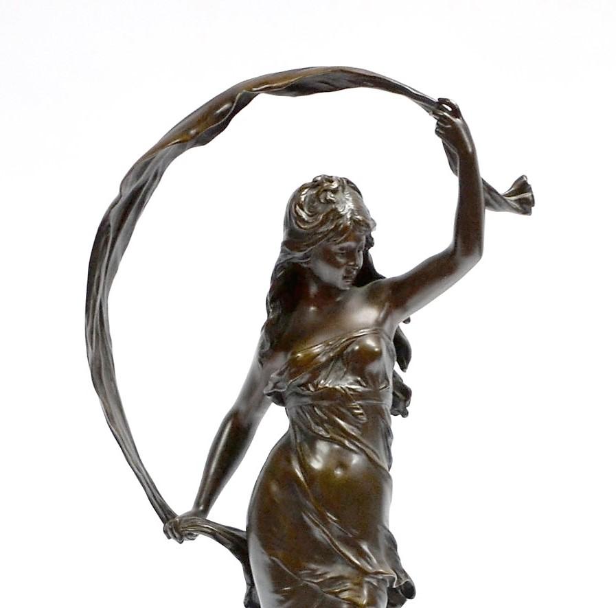 Large bronze sculpture with medal patina representing a young girl holding a scarf shaken by a light breeze. Old cast bronze based on a canted base, signed on the half sphere Auguste Moreau. On the base is affixed a cartouche bearing the inscription