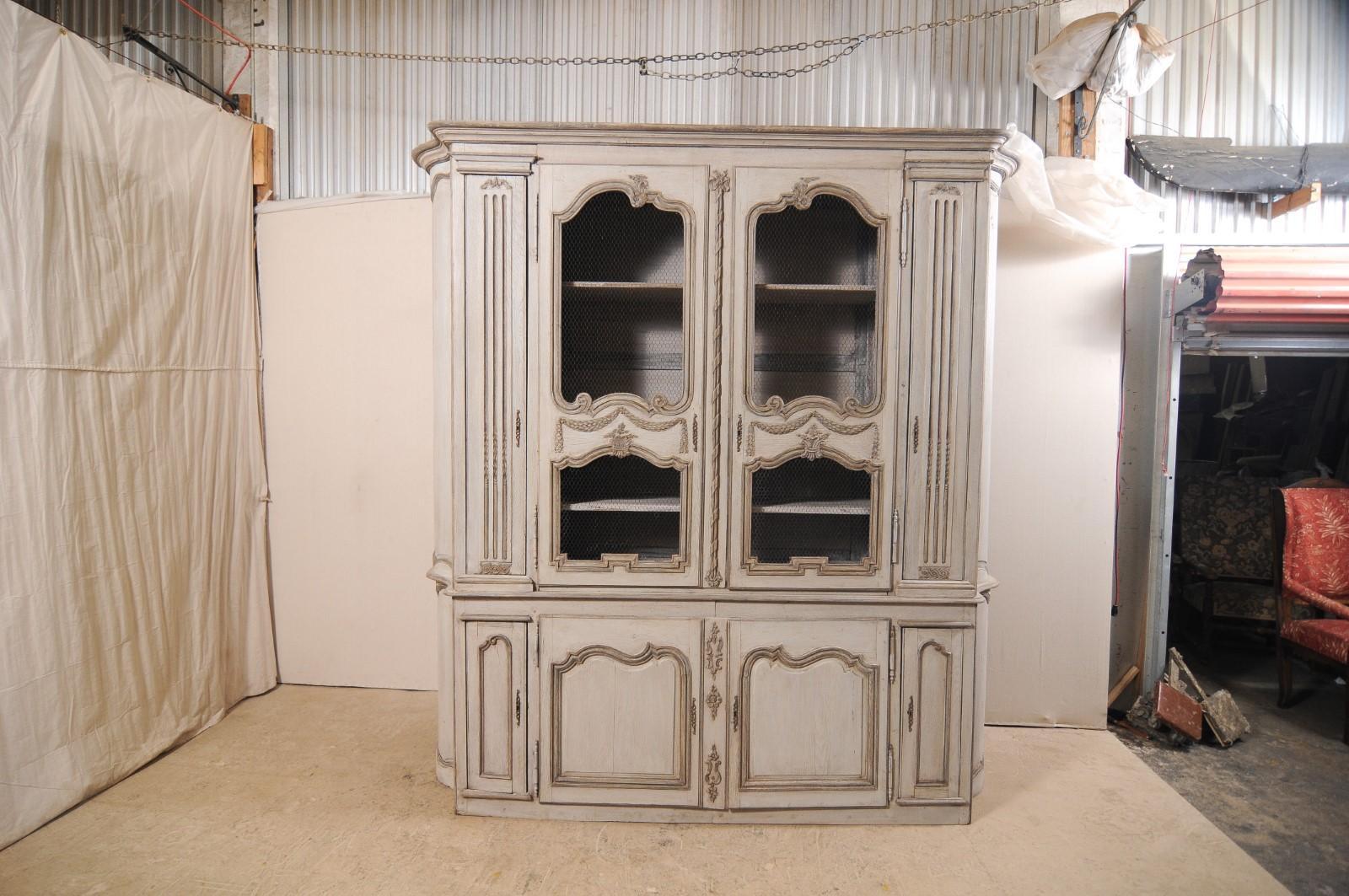 A large French carved and painted wood display and storage cabinet from the mid-20th century. This vintage French buffet à deux-corps (which is the name for a French buffet consisting of an upper and lower case, 