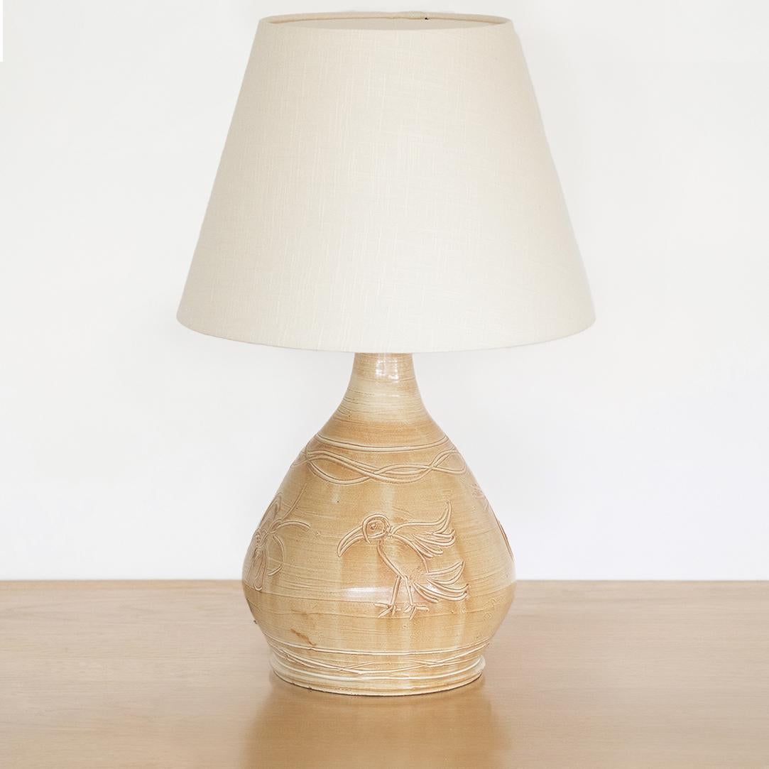 Large French ceramic etched table lamp from France, 1970's. Round ceramic base in beige and brown tones with bird and flower etched motifs. New linen shade and newly re-wired. 



