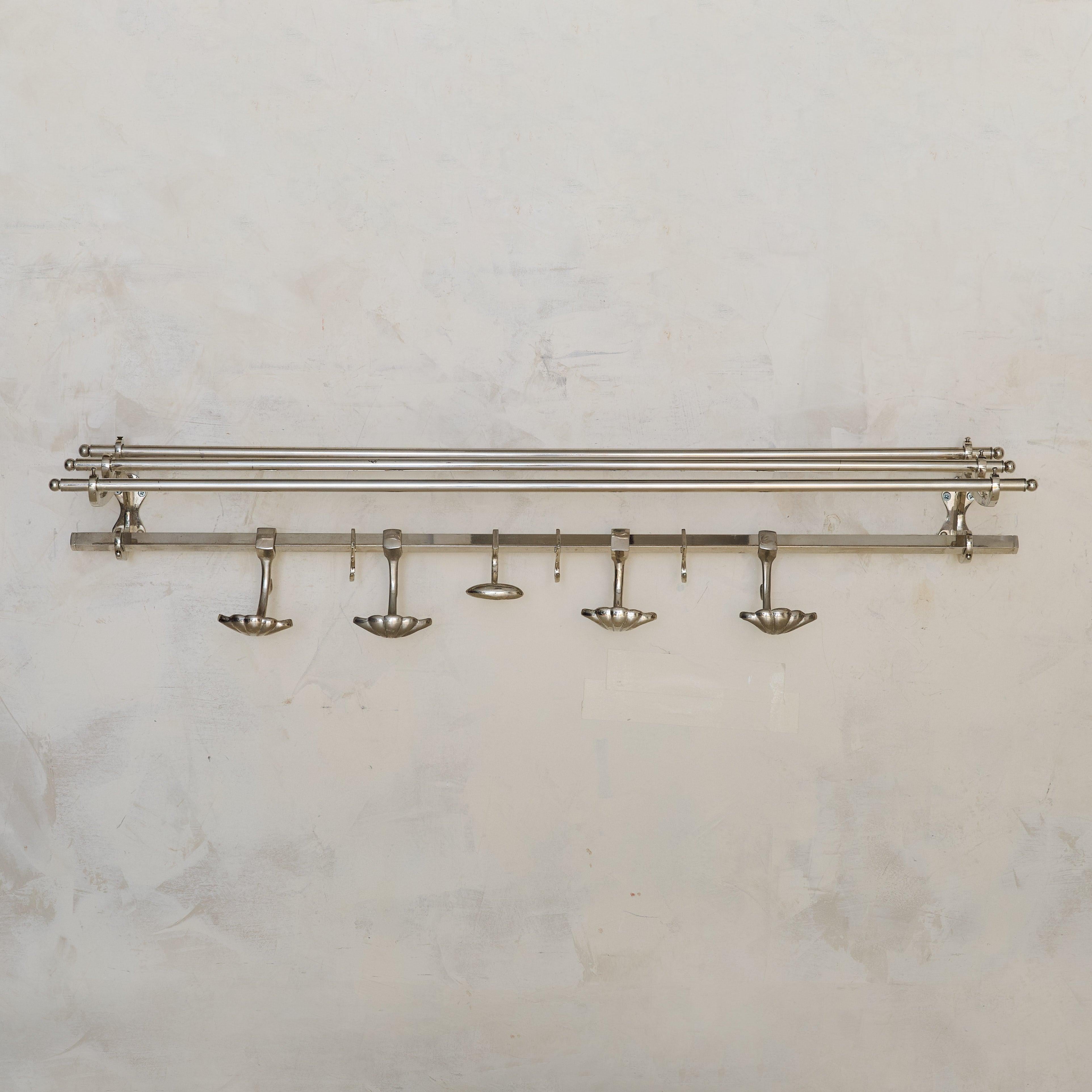 Un appendiabiti da parete francese degli anni '70, definito dalla sua forma elegante e minimalista. Realizzato in cromo, il pezzo presenta un ripiano a doppio binario per riporre cappelli o indumenti piegati, completato da una fila di ganci smerlati