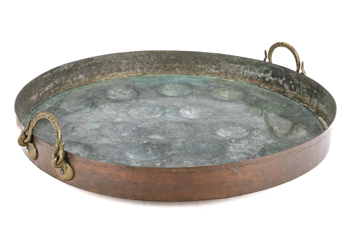 Large French copper egg or escargot poaching pan with embossed drop brass handles and 19 cup openings. Previously repurposed as a tray and comes with a glass liner. Unmarked.

Dimensions: 22
