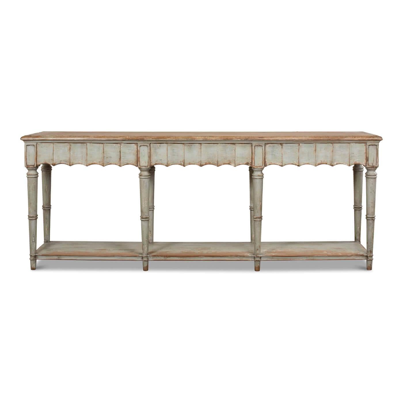 A Large French Country console table. This beautiful table has a natural top with a lightly distressed painted finish in soft sage green. The front apron of this piece has a beautiful fluted design. It has three drawers, eight turned and tapered
