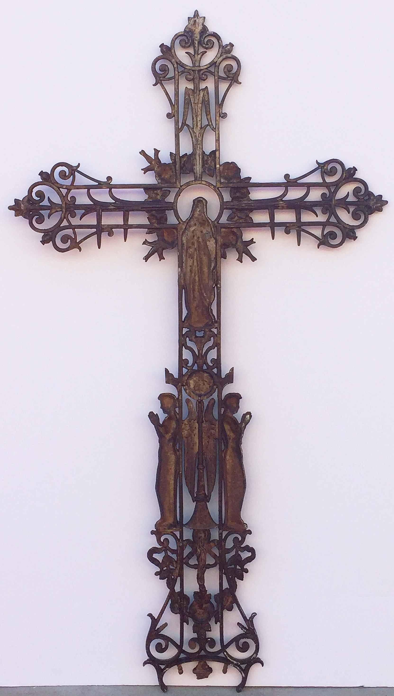 A large French cross or crucifix of cast iron with the Virgin Mary or Madonna in a wreath of flowers over two angels, with decorative scroll-work the top, arms, and base.

Dimensions are 
H 57 in
W 31 1/4 in
D 2 in.